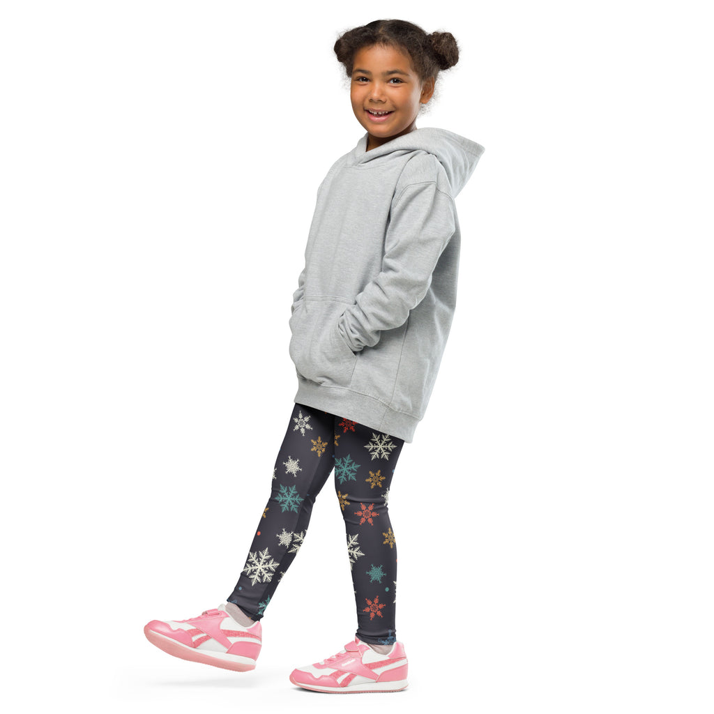 A child wearing festive kids christmas leggings with colorful snowflakes paired with a light gray hooded sweatshirt