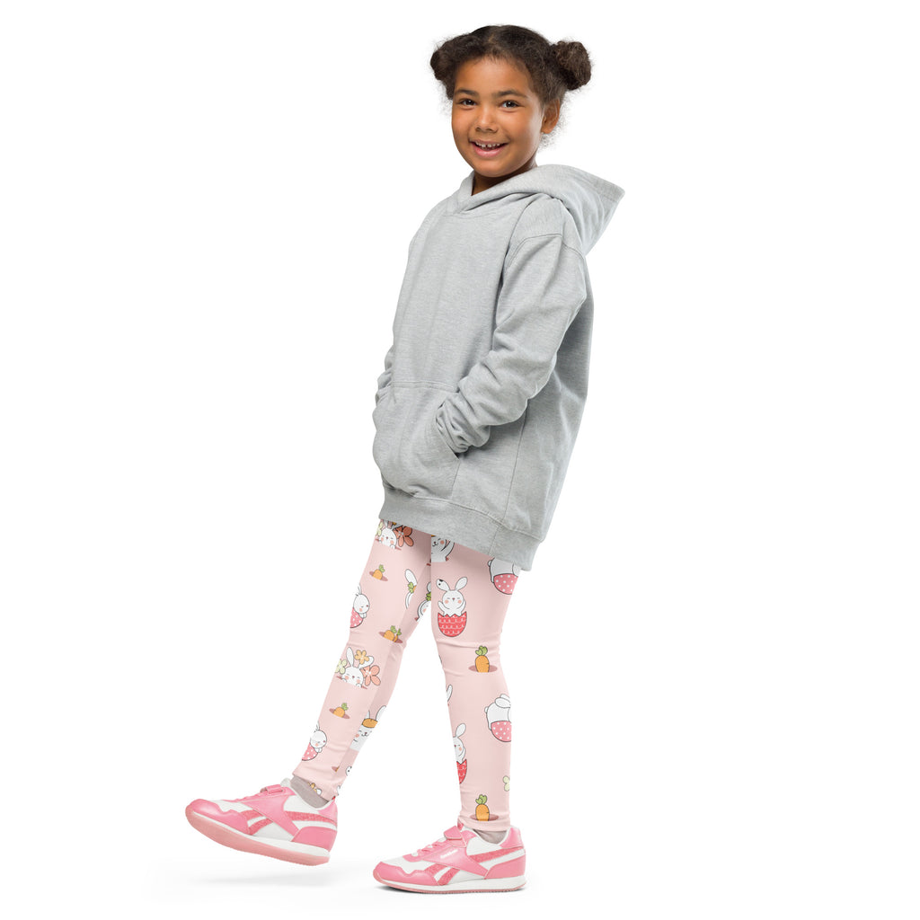 A young girl wearing light gray hooded sweatshirt and pink buttery soft kids Easter bunny pattern leggings