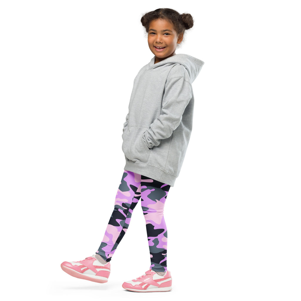 A young girl wearing girls purple camouflage buttery soft leggings with pink and black pattern and pink sneakers