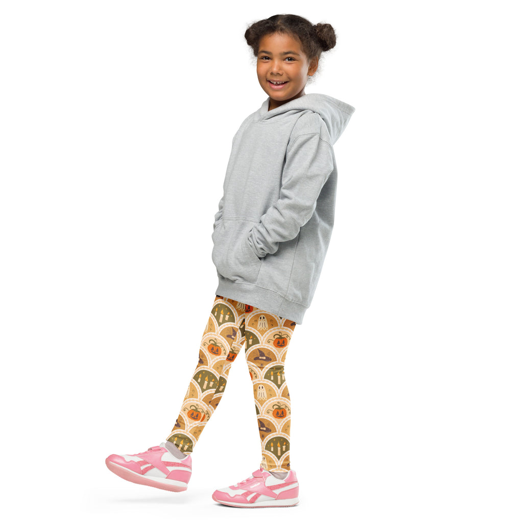 A child wearing kids autumn themed halloween buttery soft leggings with pumpkins ghosts and bats in orange brown tones