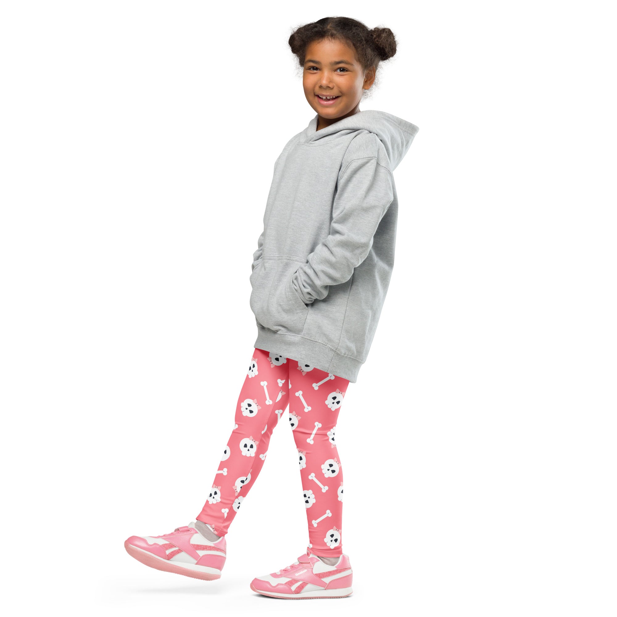 A young girl wearing pink skull halloween buttery soft leggings with gray hooded sweatshirt and matching pink sneakers