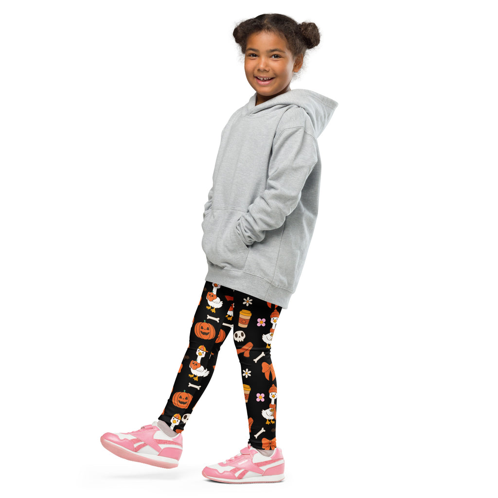 A child wearing kids goose halloween buttery soft leggings in black with orange halloween prints and a light gray hoodie