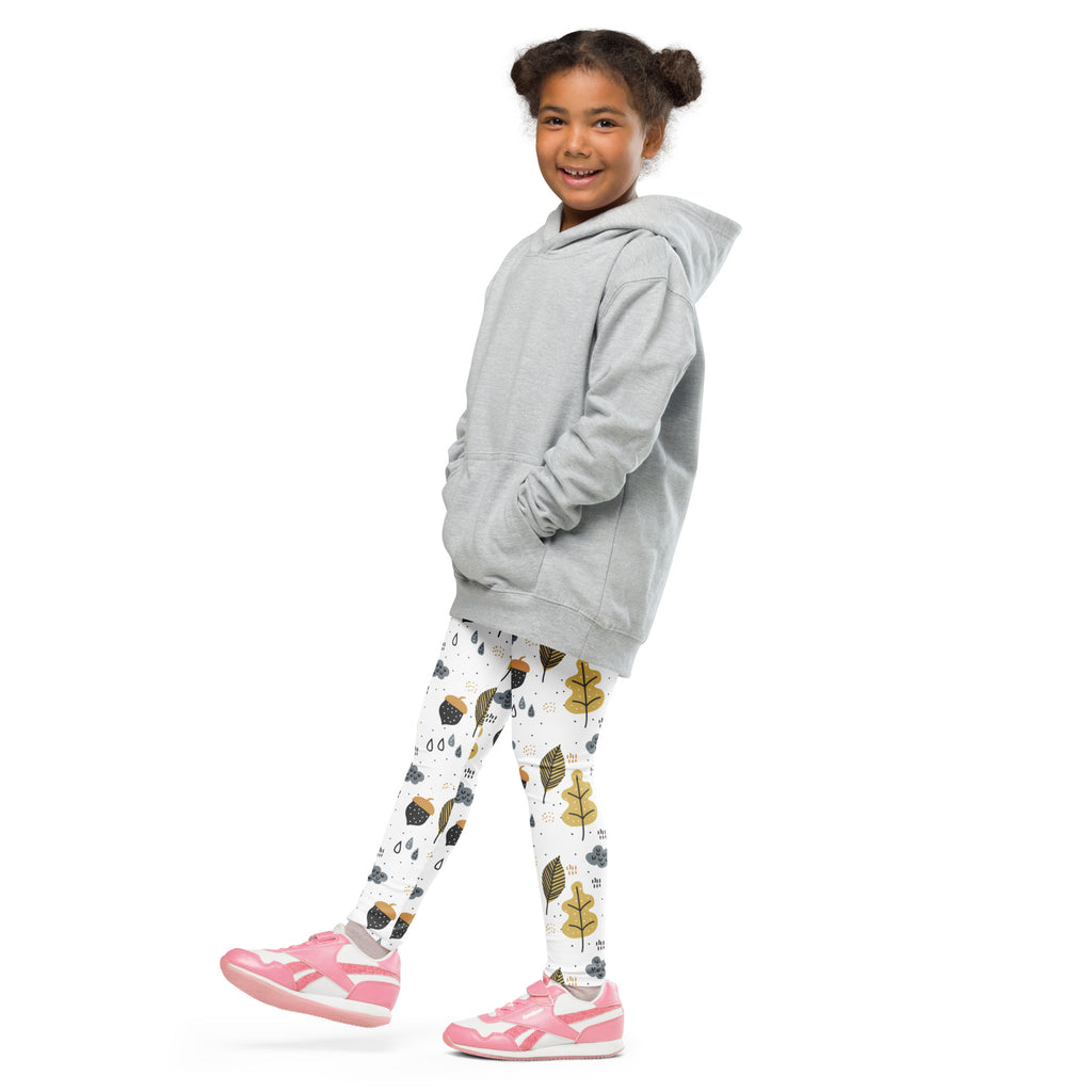 A young girl wearing light gray hooded sweatshirt and buttery soft white leggings with gold autumn leaf patterns
