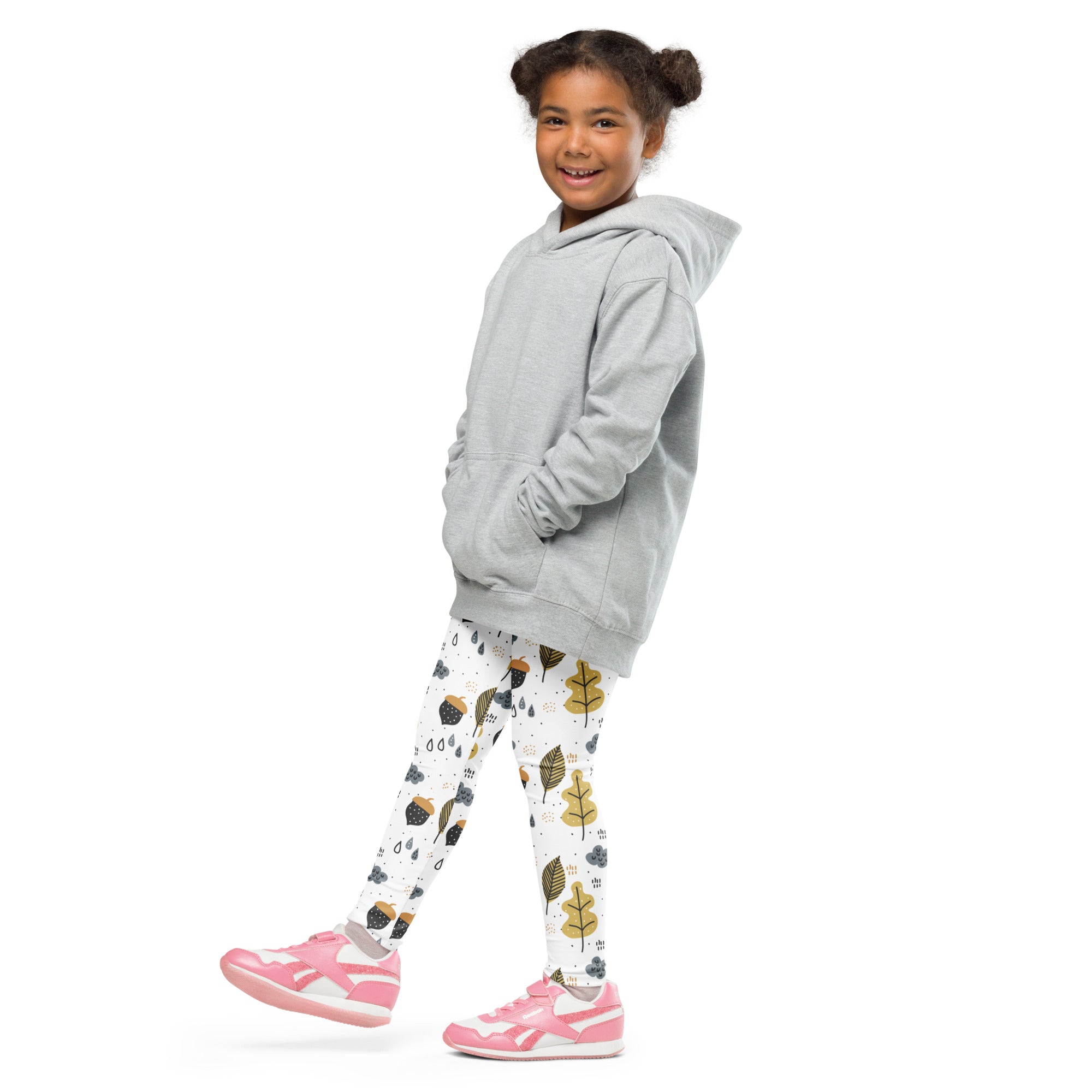 A young girl wearing light gray hooded sweatshirt and buttery soft white leggings with gold autumn leaf patterns