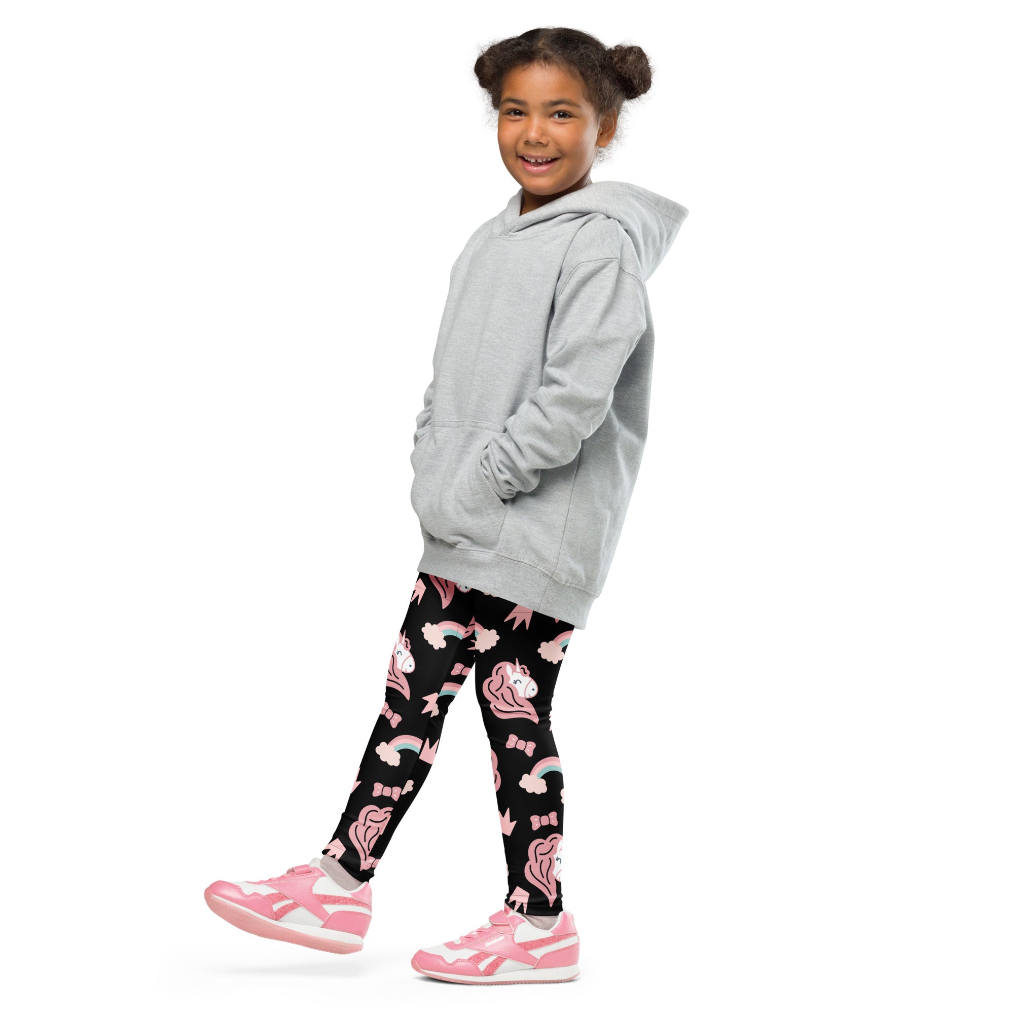 A child wearing girls unicorn rainbow buttery soft black leggings with pink unicorn rainbow and bow patterns