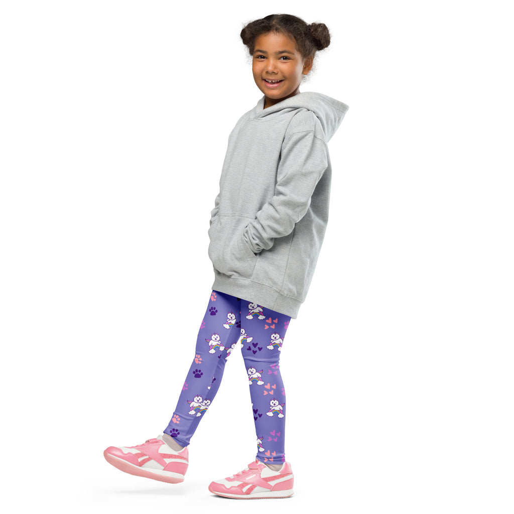 A young girl wearing girls purple caticorn buttery soft leggings with white cartoon characters and pink paw prints