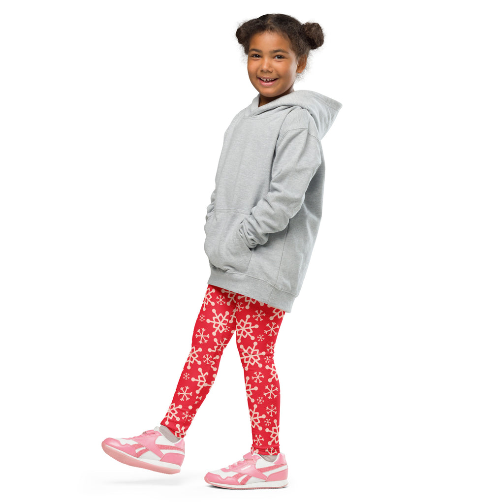 A child wearing kids red snowflake buttery soft leggings in red with white snowflake patterns and a light gray hoodie