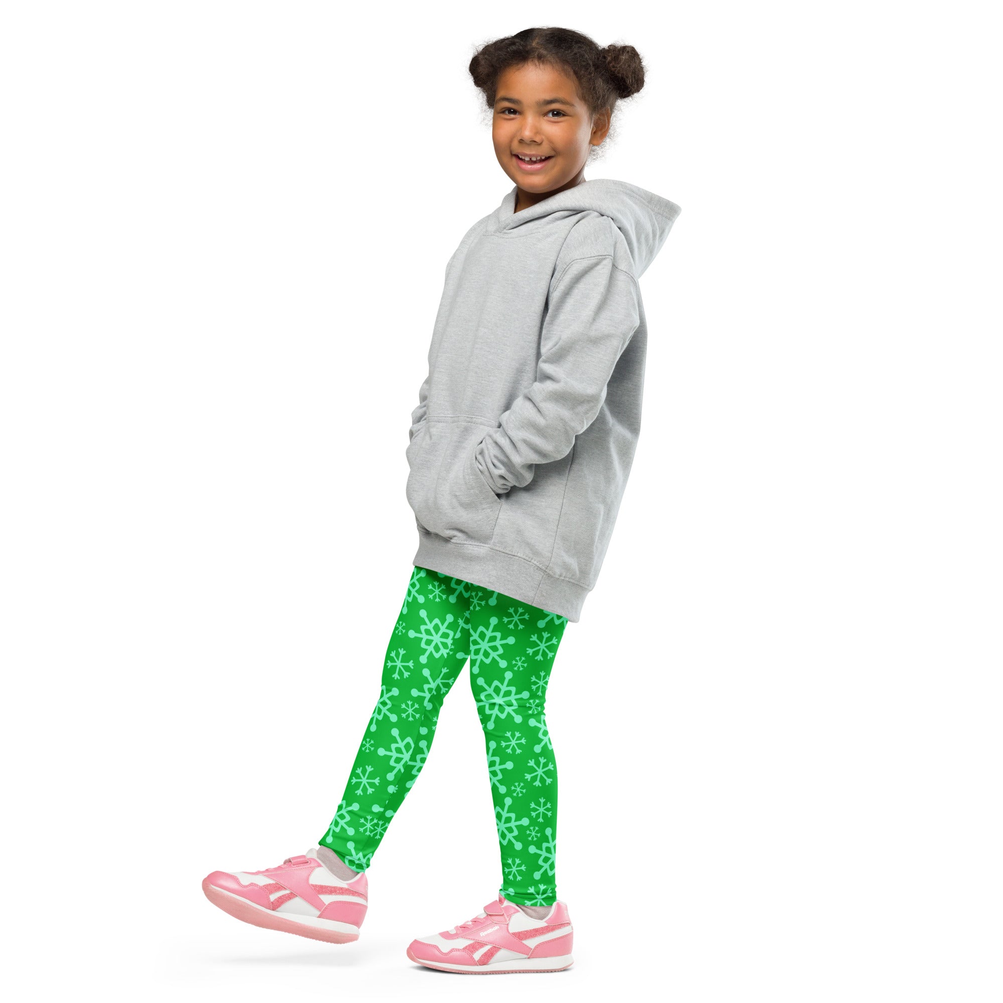 A child wearing kids green snowflake buttery soft leggings in bright green with white snowflake patterns and a gray hooded sweatshirt