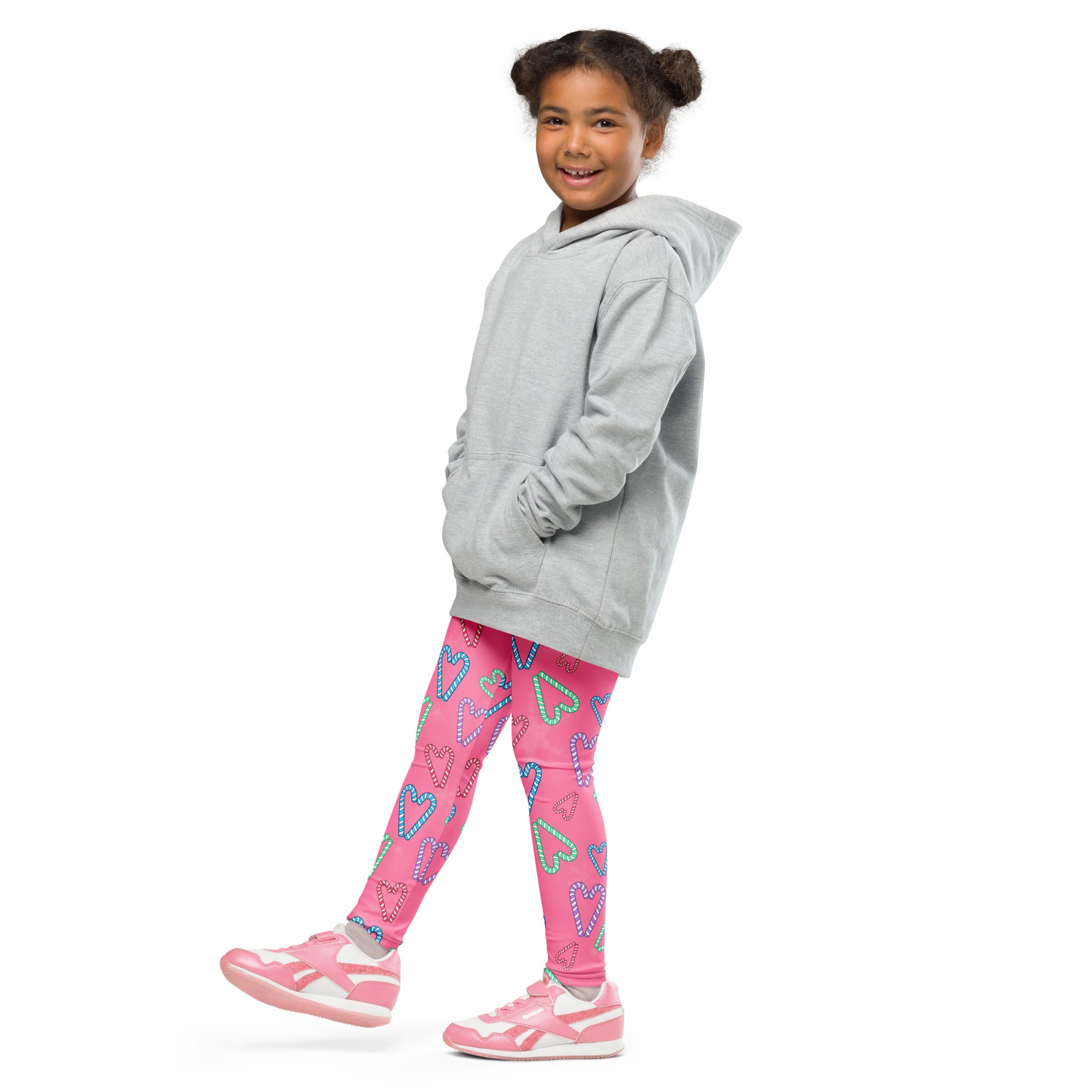 A child wearing girls pink candy cane heart buttery soft leggings in bright pink with outlined hearts and a gray hoodie