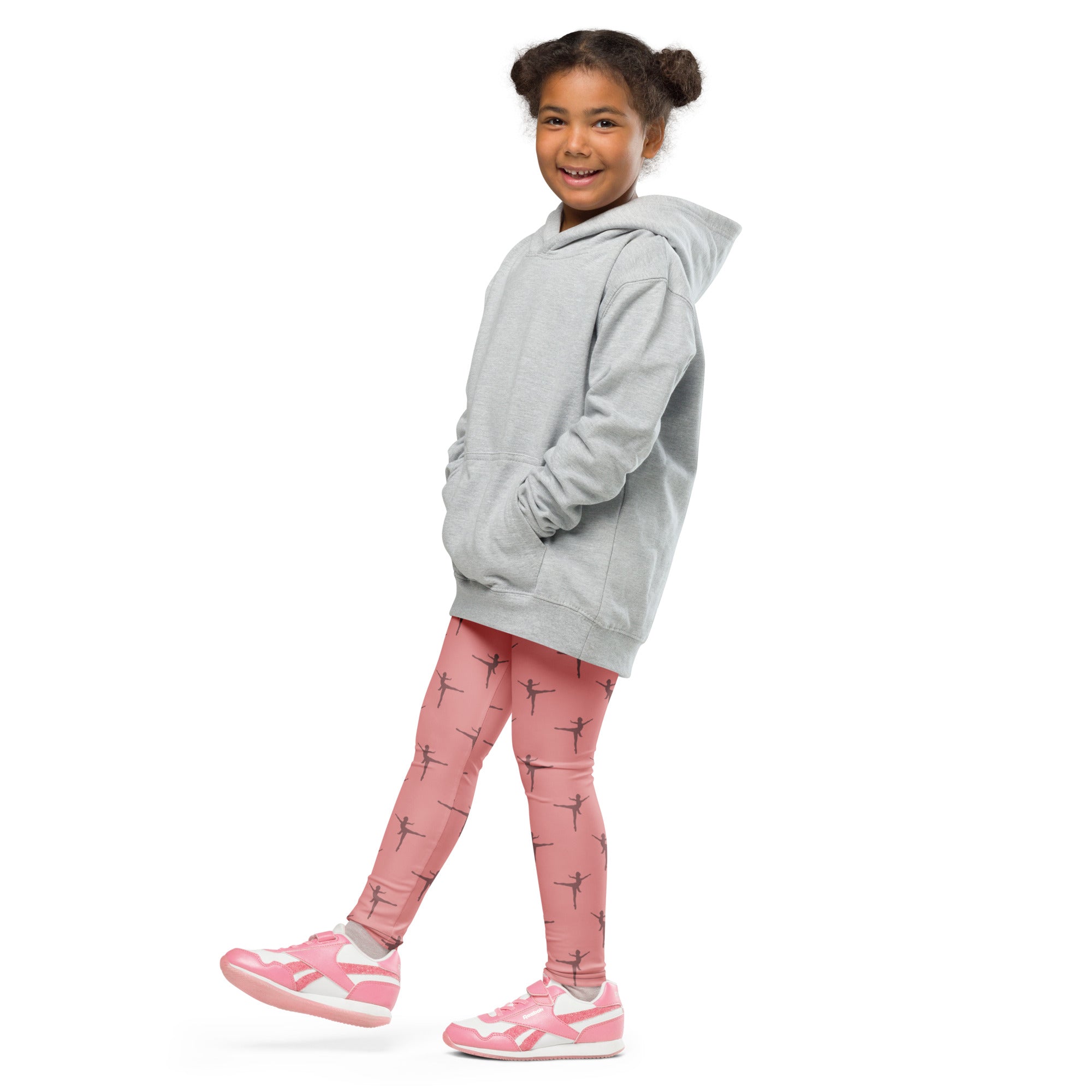 A young girl wearing girls pink dance buttery soft leggings with black ballet dancer prints and matching pink sneakers