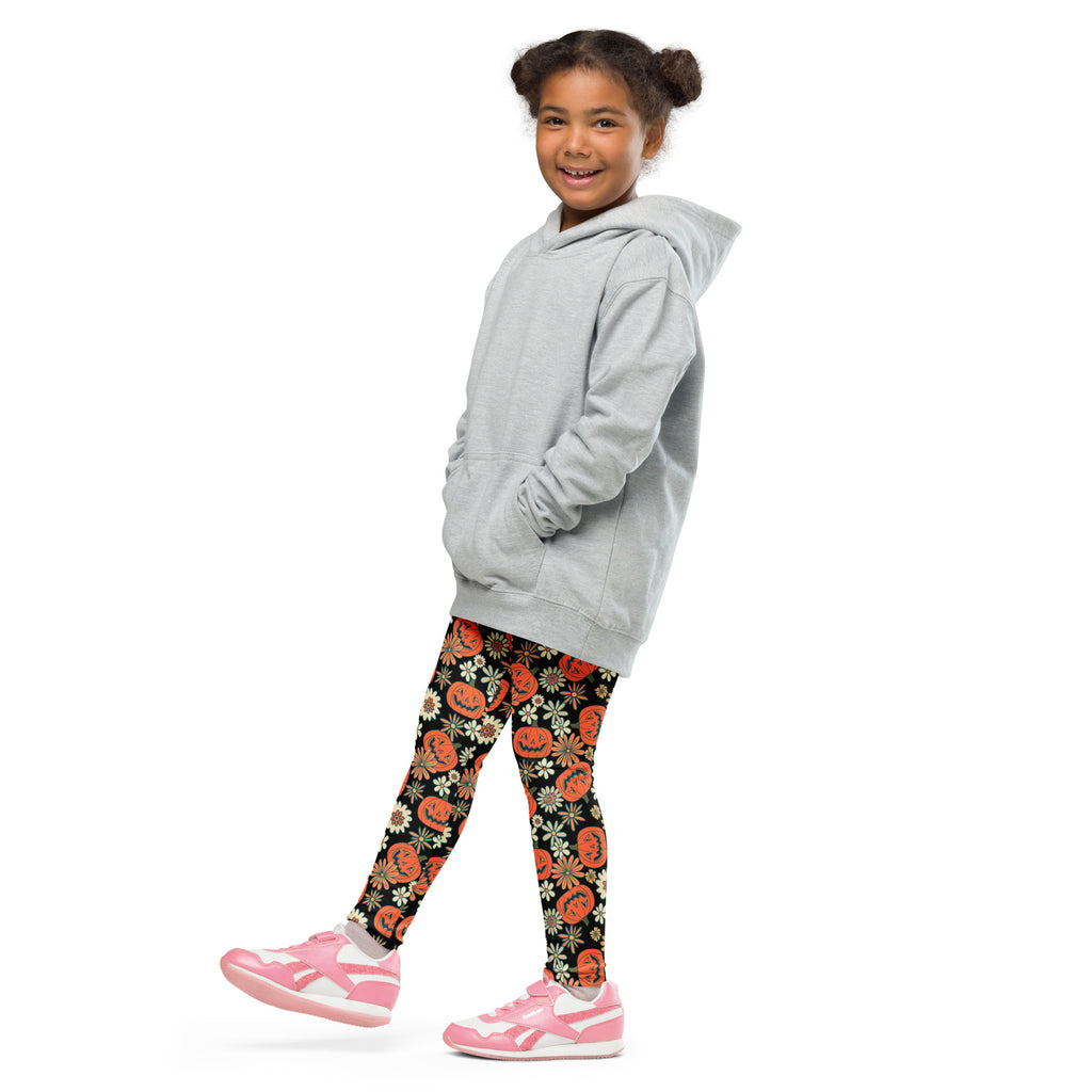 A child wearing kids vintage Halloween pumpkin floral buttery soft black leggings with orange pumpkin faces and white flowers