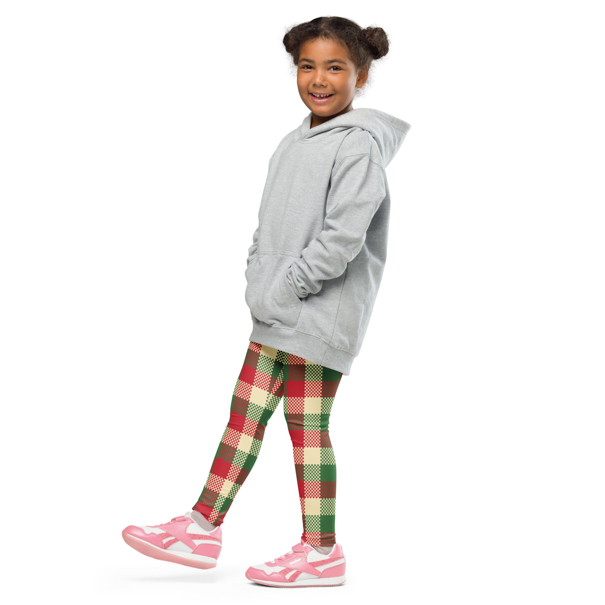 A young girl wearing kids Christmas plaid buttery soft leggings in red green and cream with a light gray hooded sweatshirt