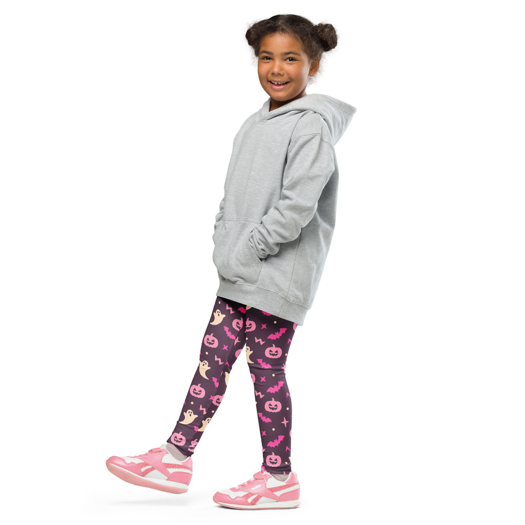 A child wearing buttery soft girls purple and pink halloween leggings paired with a light gray hooded sweatshirt and pink sneakers