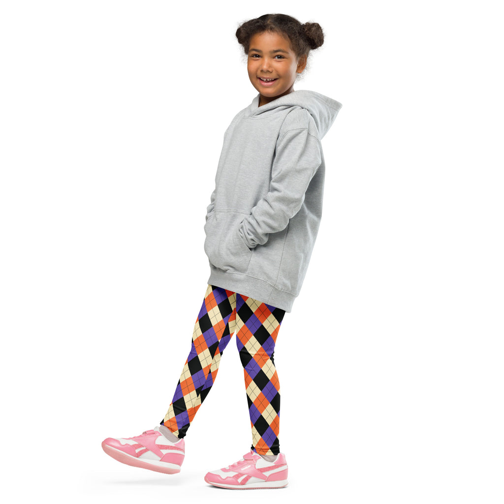A young girl wears kids halloween argyle buttery soft leggings in orange purple black and cream with a gray hooded sweatshirt