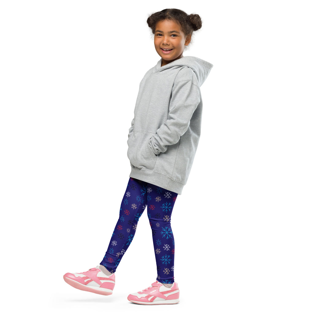 A young girl wearing kids snowflake pattern buttery soft dark blue leggings with colorful snowflakes and a gray hoodie