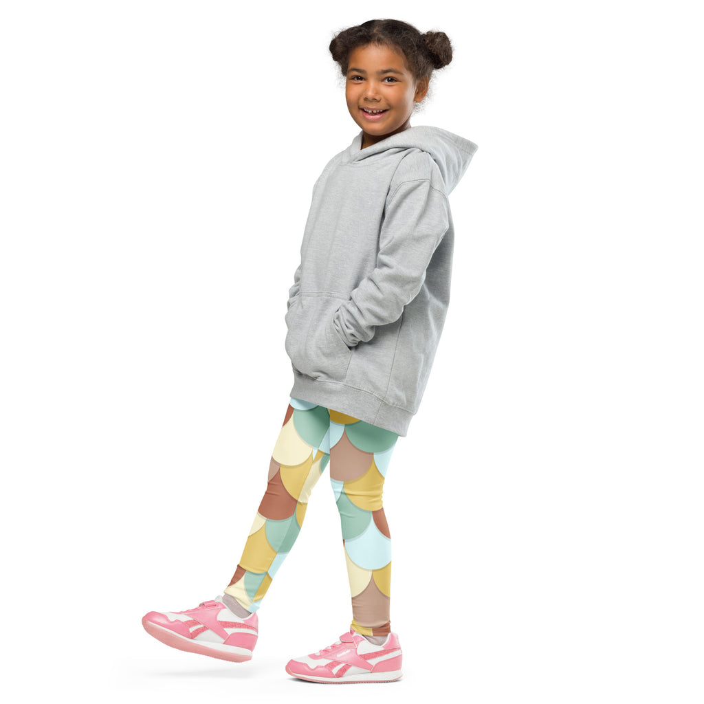 A young girl wearing girls green and brown mermaid buttery soft leggings with a soft gray hooded sweatshirt