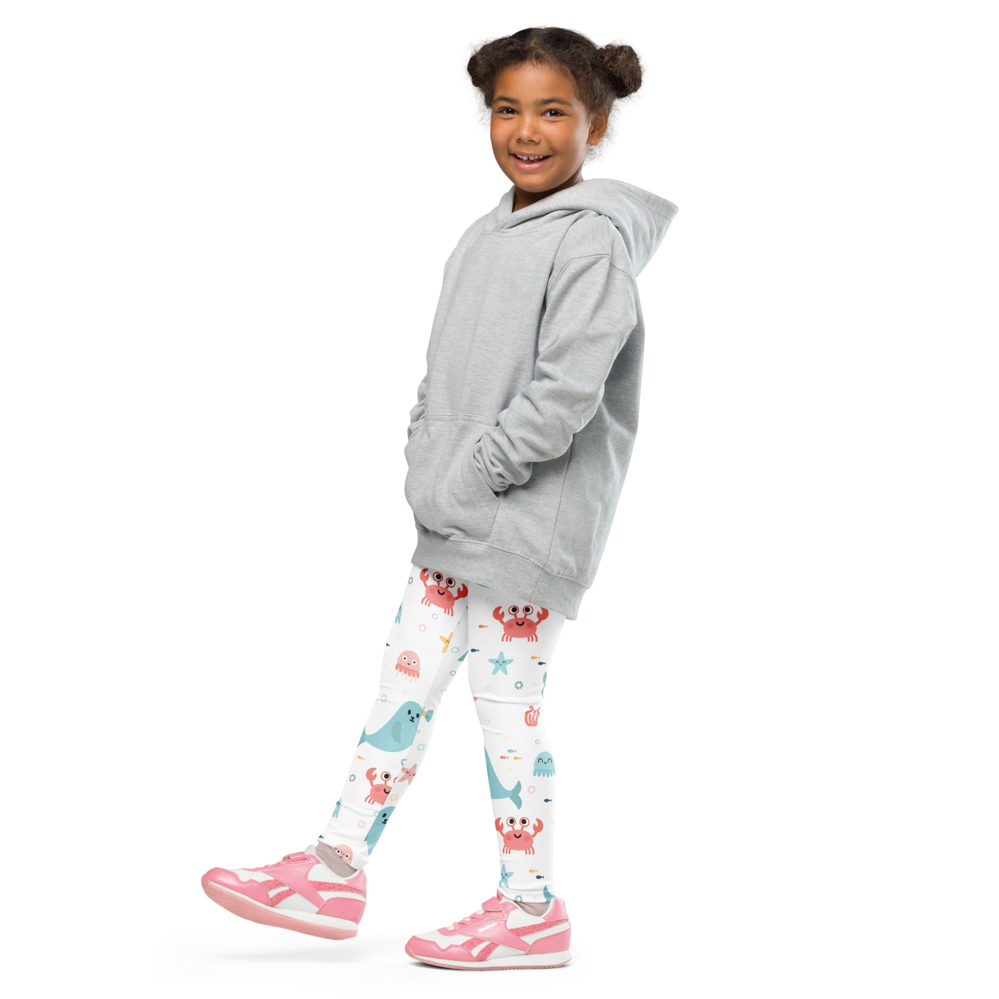 A child wearing girls ocean animal buttery soft white leggings with colorful sea creatures and pink sneakers