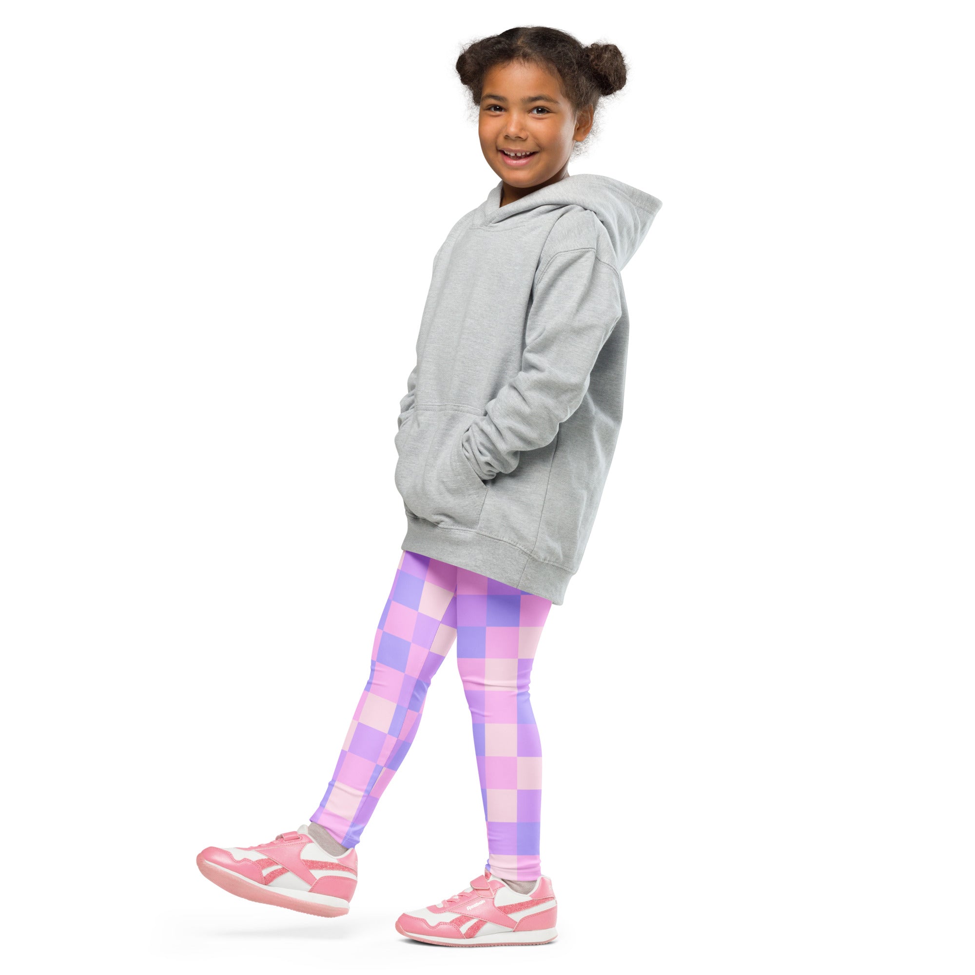 A young girl wearing purple checkered buttery soft leggings with a gray hoodie and pink sneakers