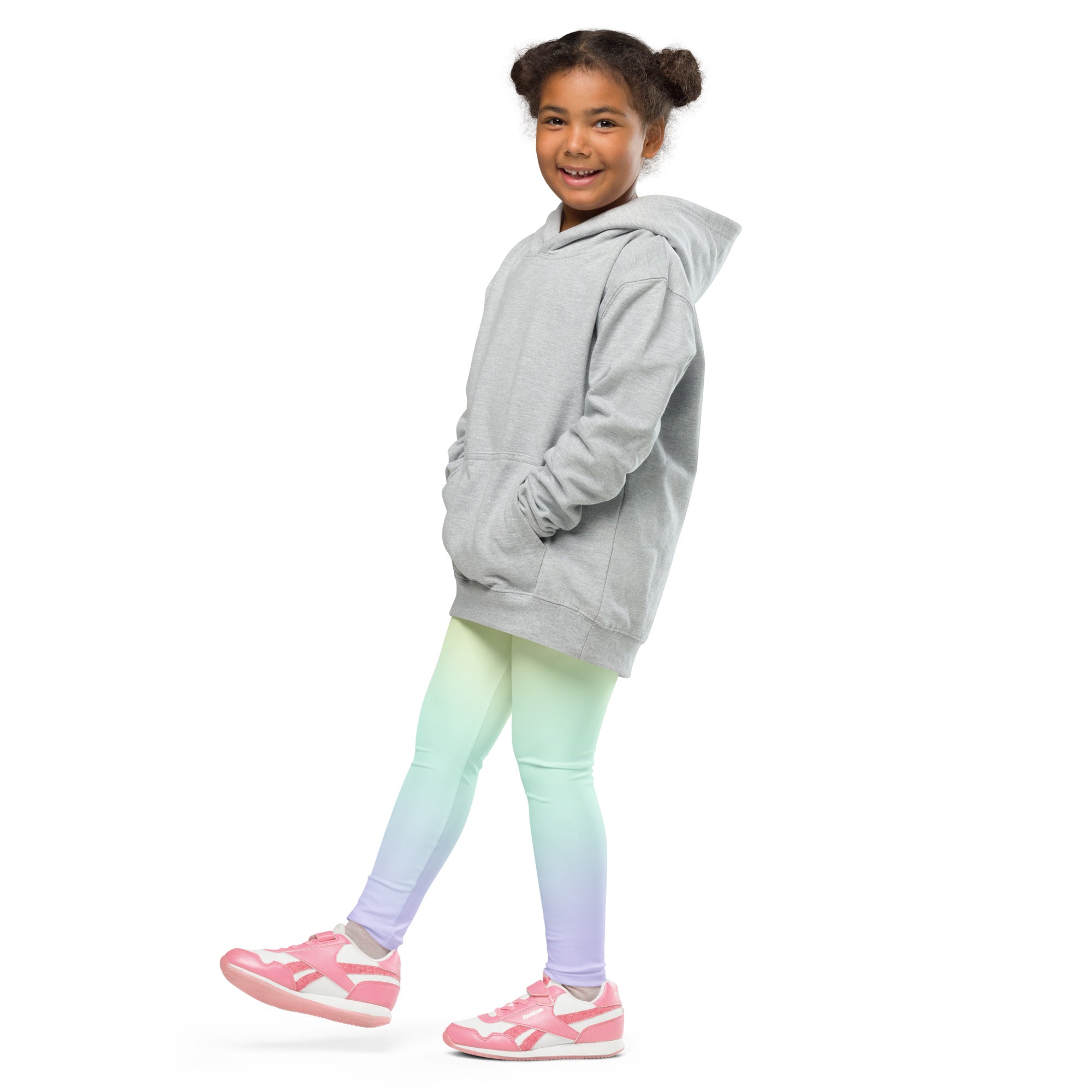 A child wearing girls pastel rainbow buttery soft leggings in a mint green to lavender gradient with a gray hooded sweatshirt