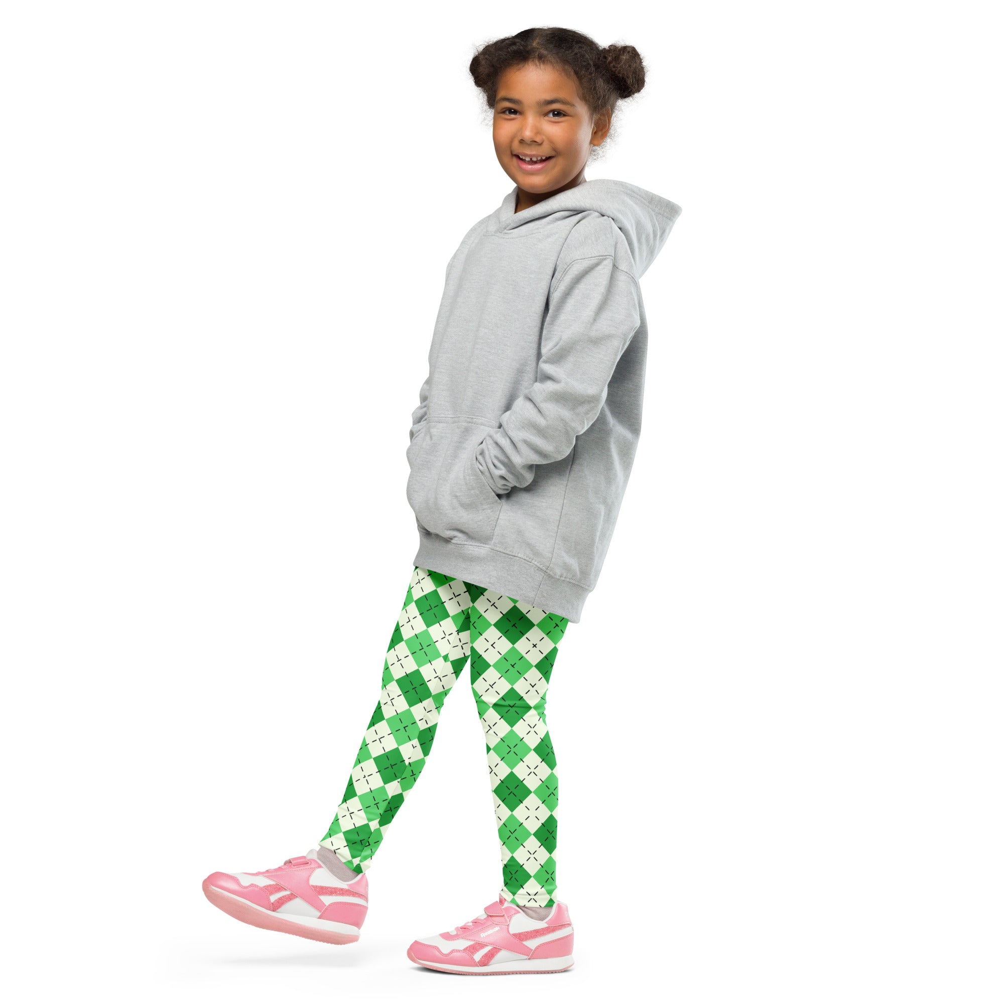 A young girl wearing green argyle buttery soft leggings with pink sneakers and a light gray hooded sweatshirt