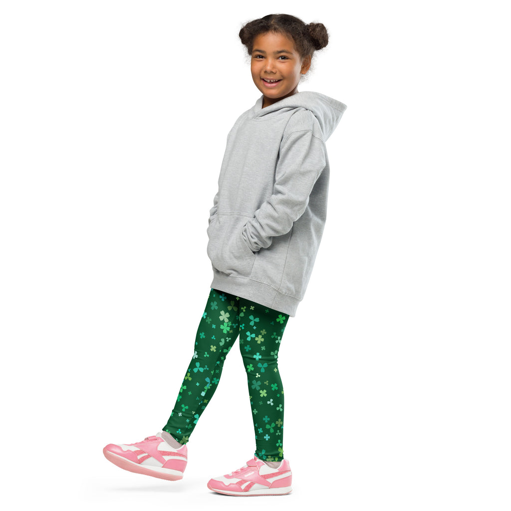 A child wearing girls teal and green shamrock buttery soft leggings with a light gray hooded sweatshirt