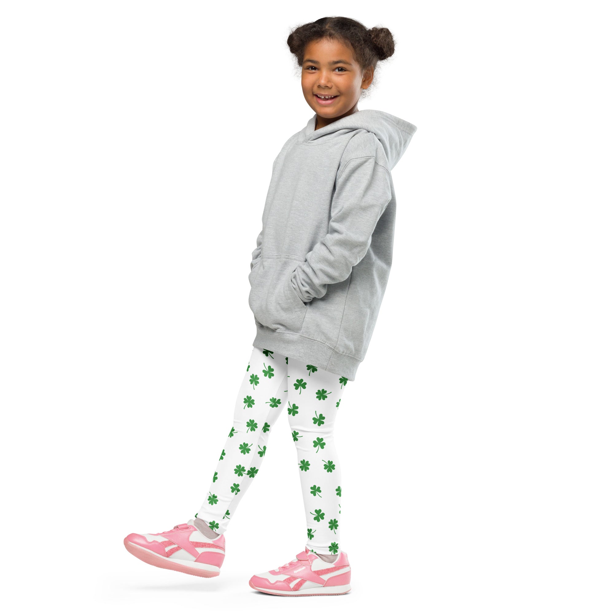 A young girl wearing girls minimal green clover buttery soft leggings in white with green shamrocks and a gray hoodie
