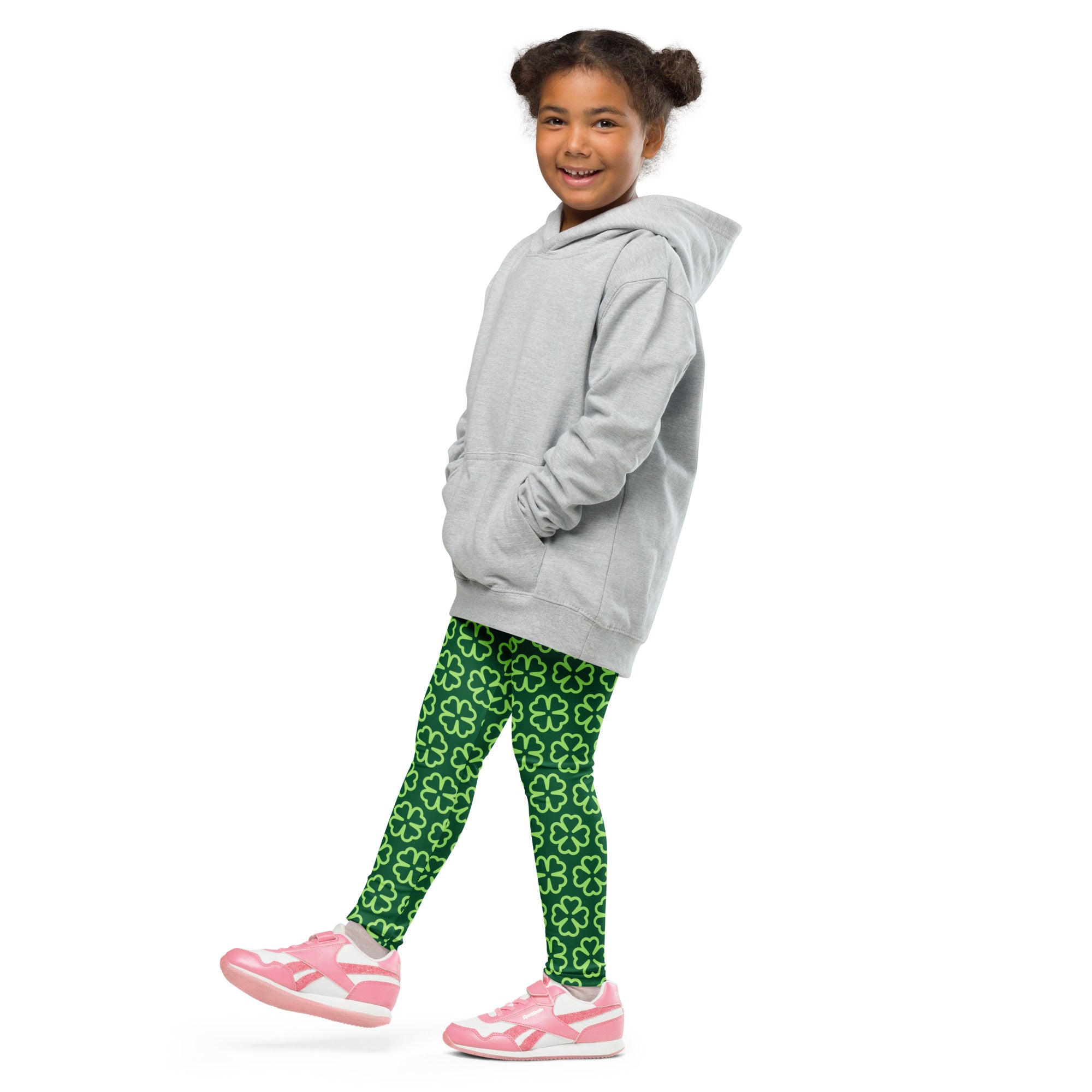 A child wearing dark green buttery soft leggings with white shamrocks paired with a gray hoodie and pink shoes