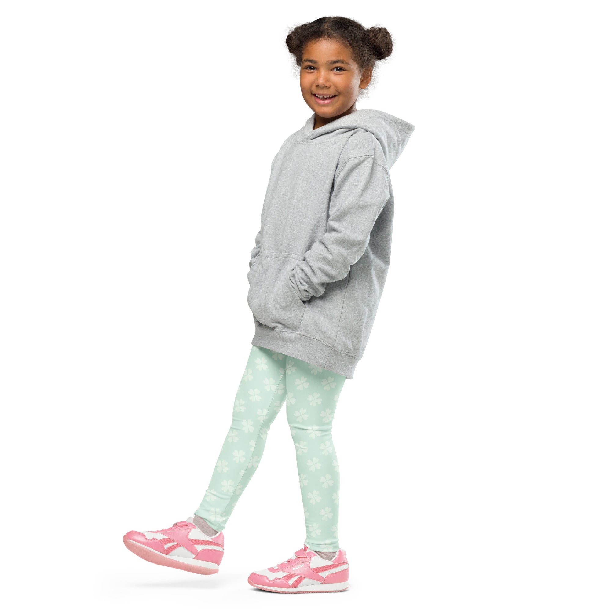 A child wearing mint shamrock buttery soft leggings with white stars and a light gray hooded sweatshirt