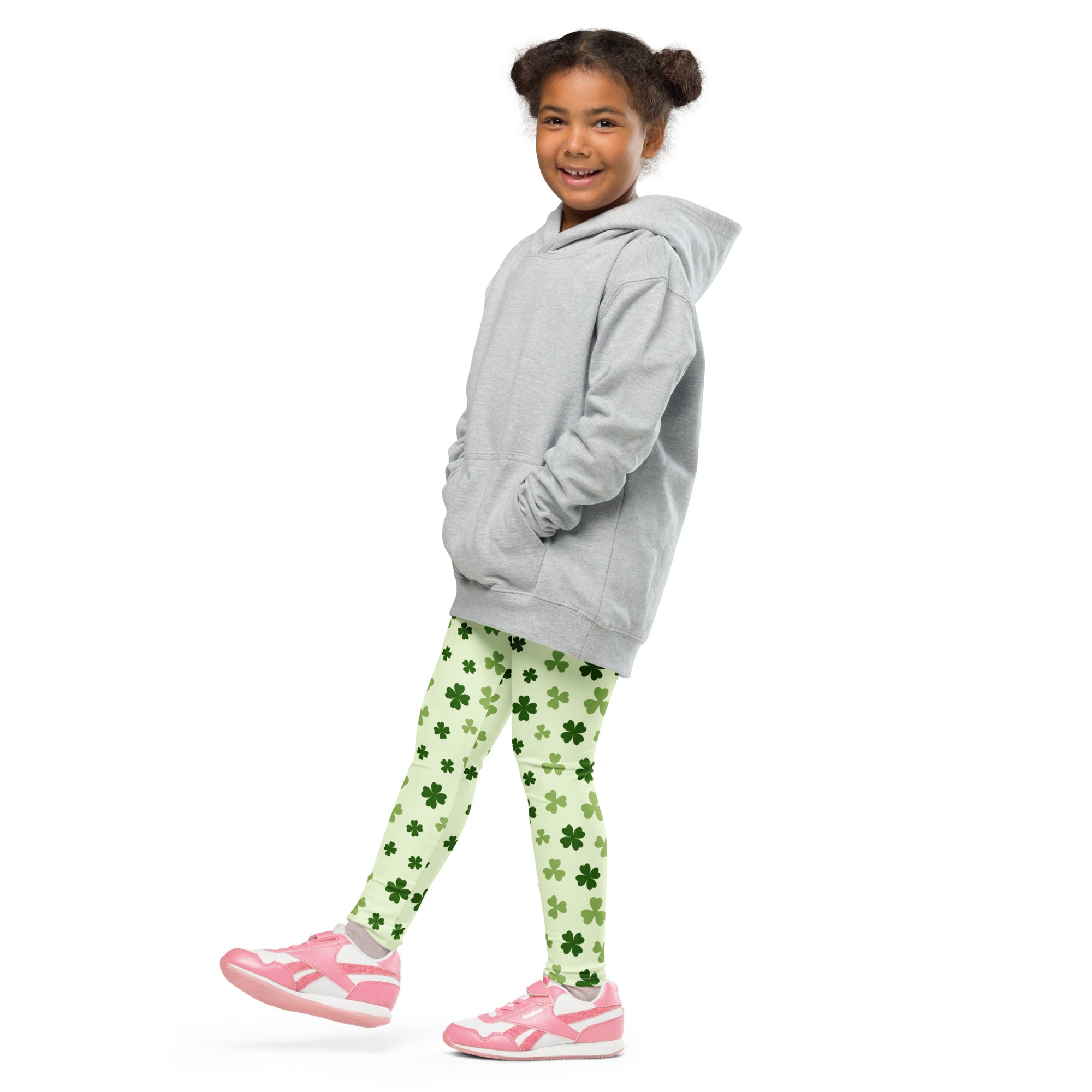 A child wearing girls light green shamrock buttery soft leggings with dark green patterns and a gray hooded sweatshirt