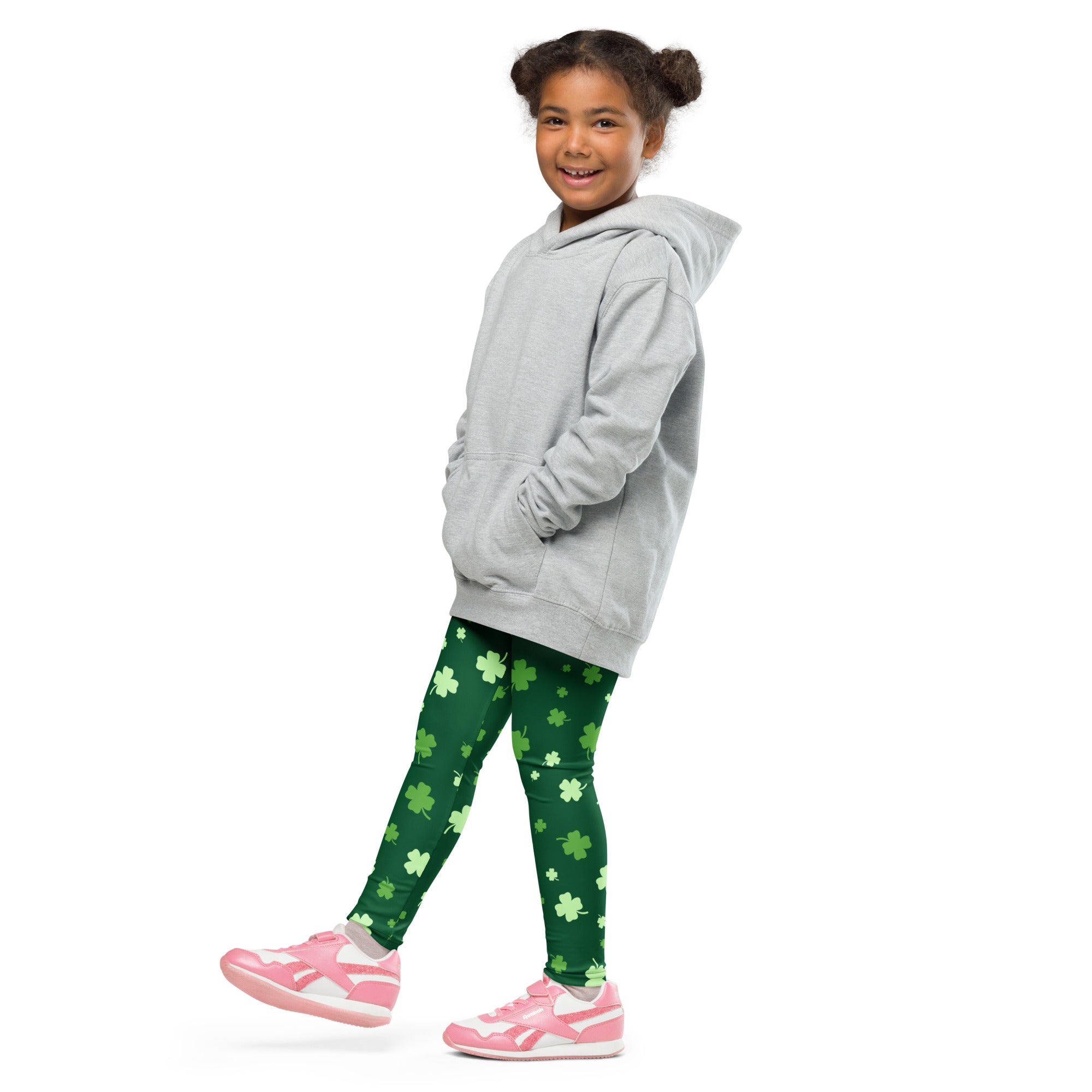 A young girl wearing green girls lucky clover St Patricks Day buttery soft leggings with shamrock patterns
