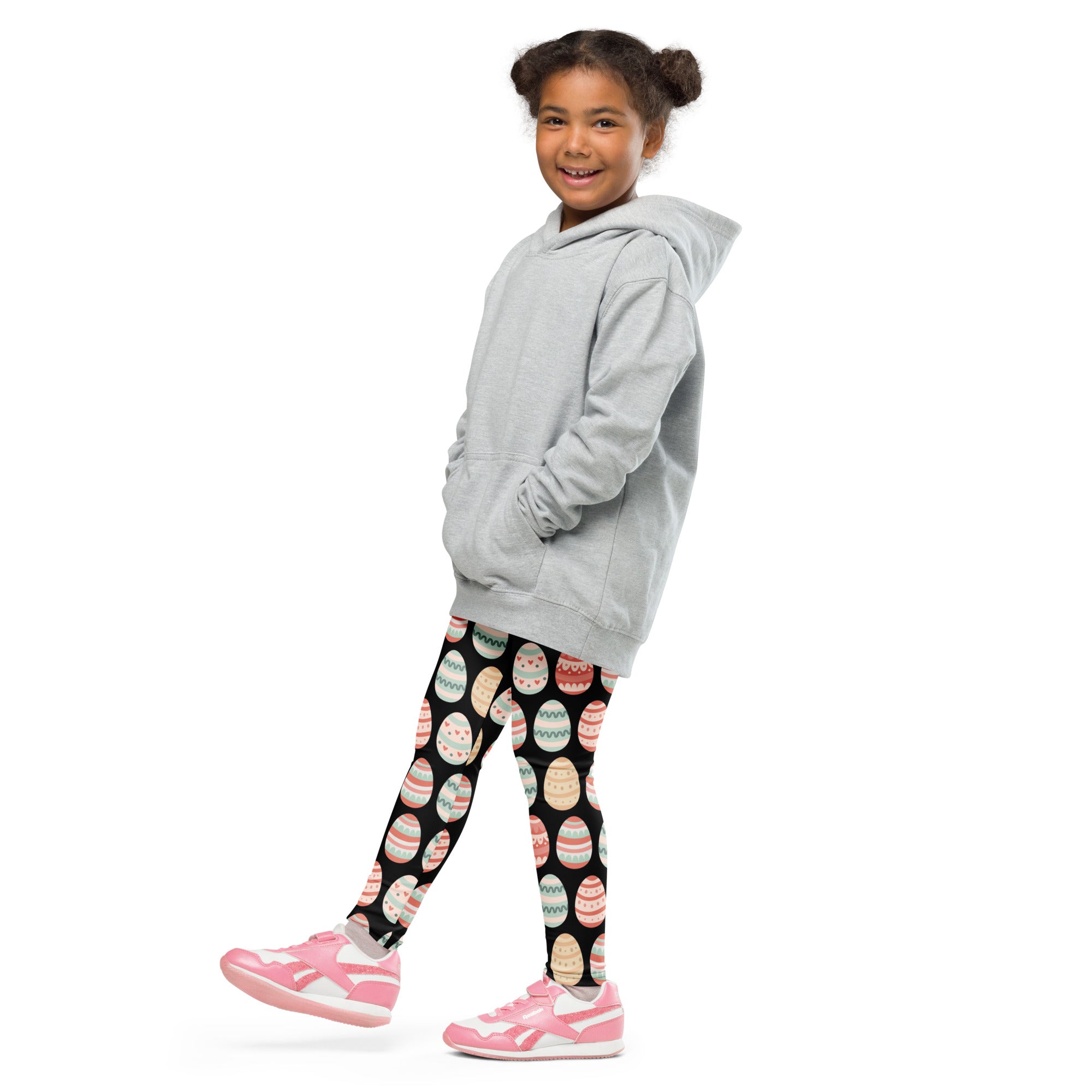 A child wearing girls black pastel Easter egg buttery soft leggings with colorful egg patterns and a gray hooded sweatshirt