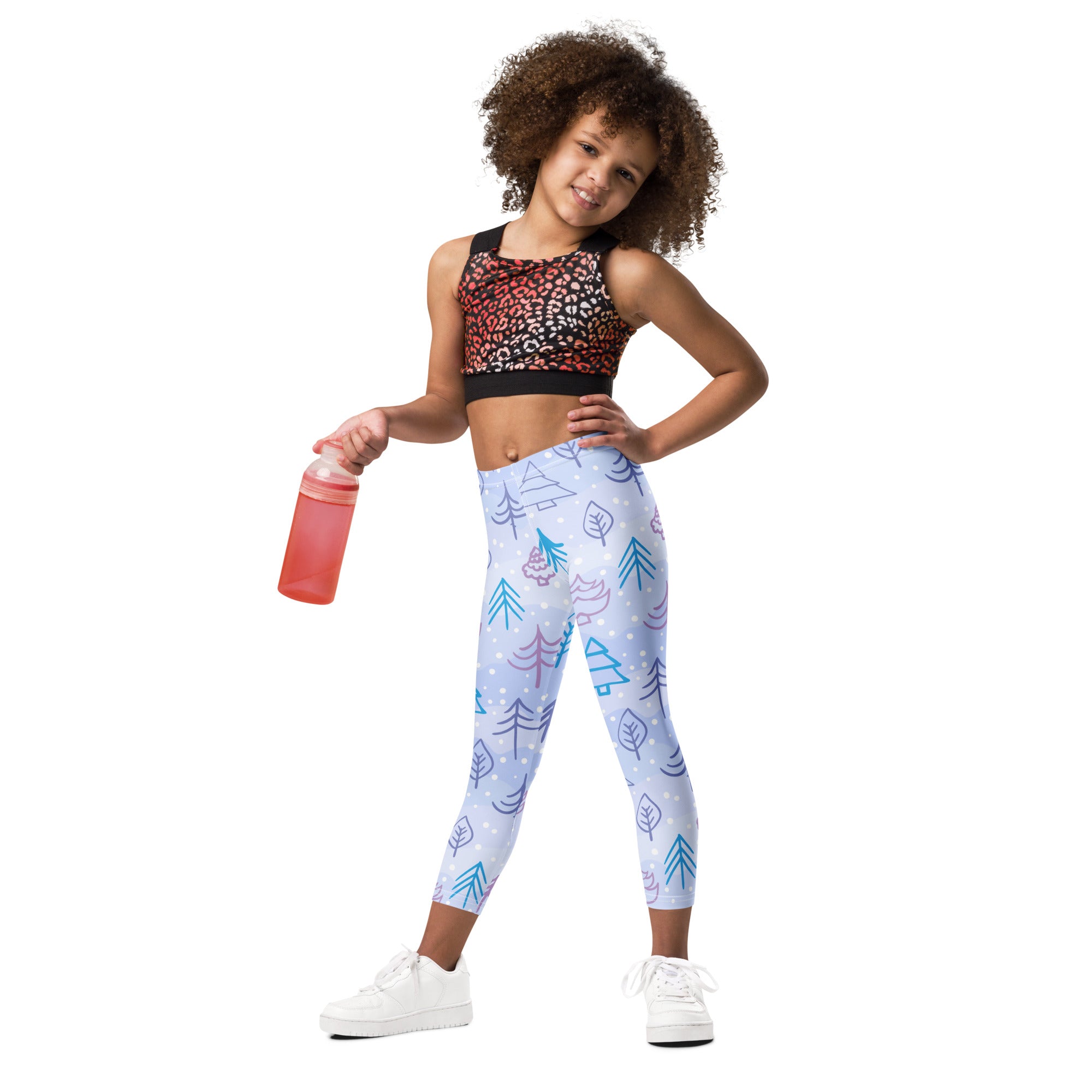 A child wearing kids snowy forest winter buttery soft leggings in light blue with teal and purple trees paired with a black and red leopard-print sports bra