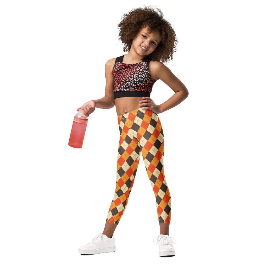 A young girl wearing kids fall argyle buttery soft orange black and beige leggings paired with a leopard-print sports bra