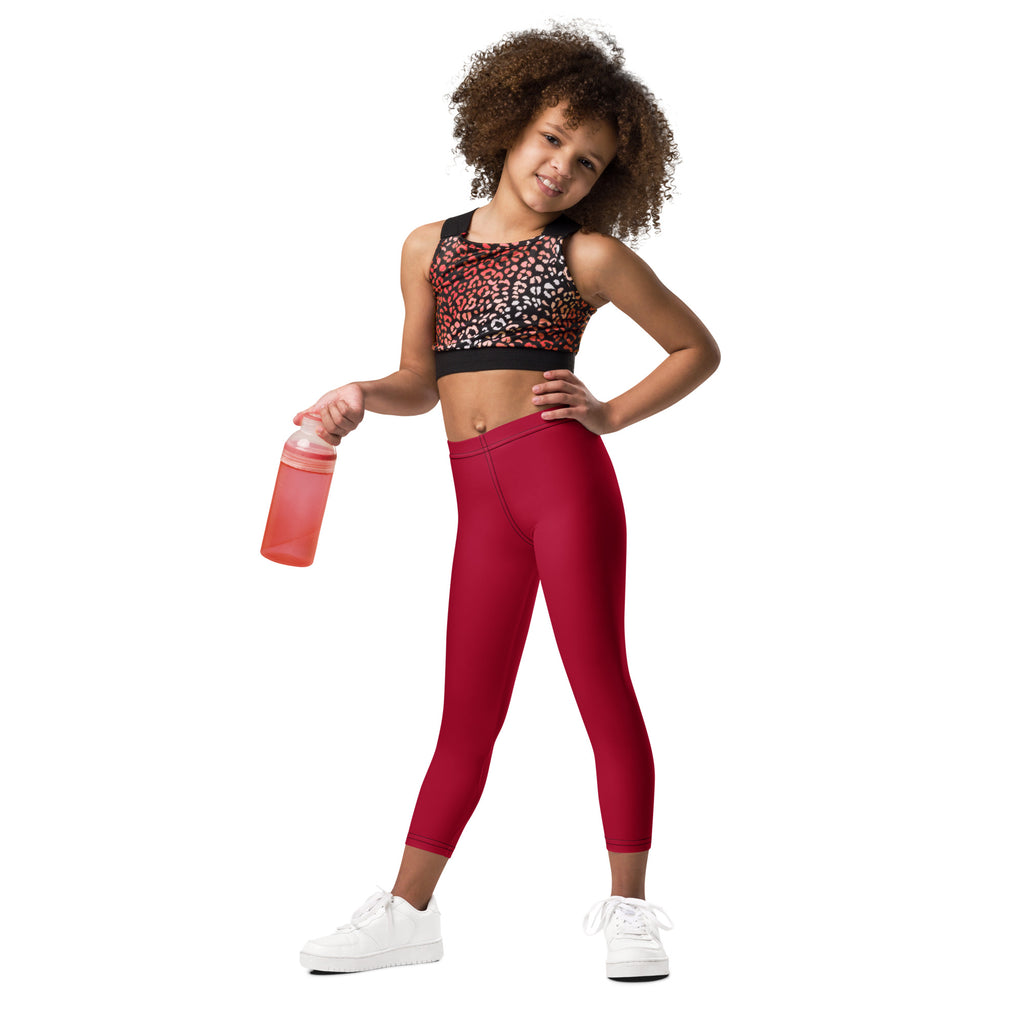 A young girl wearing kids dark red buttery soft leggings and a leopard print sports bra with black trim