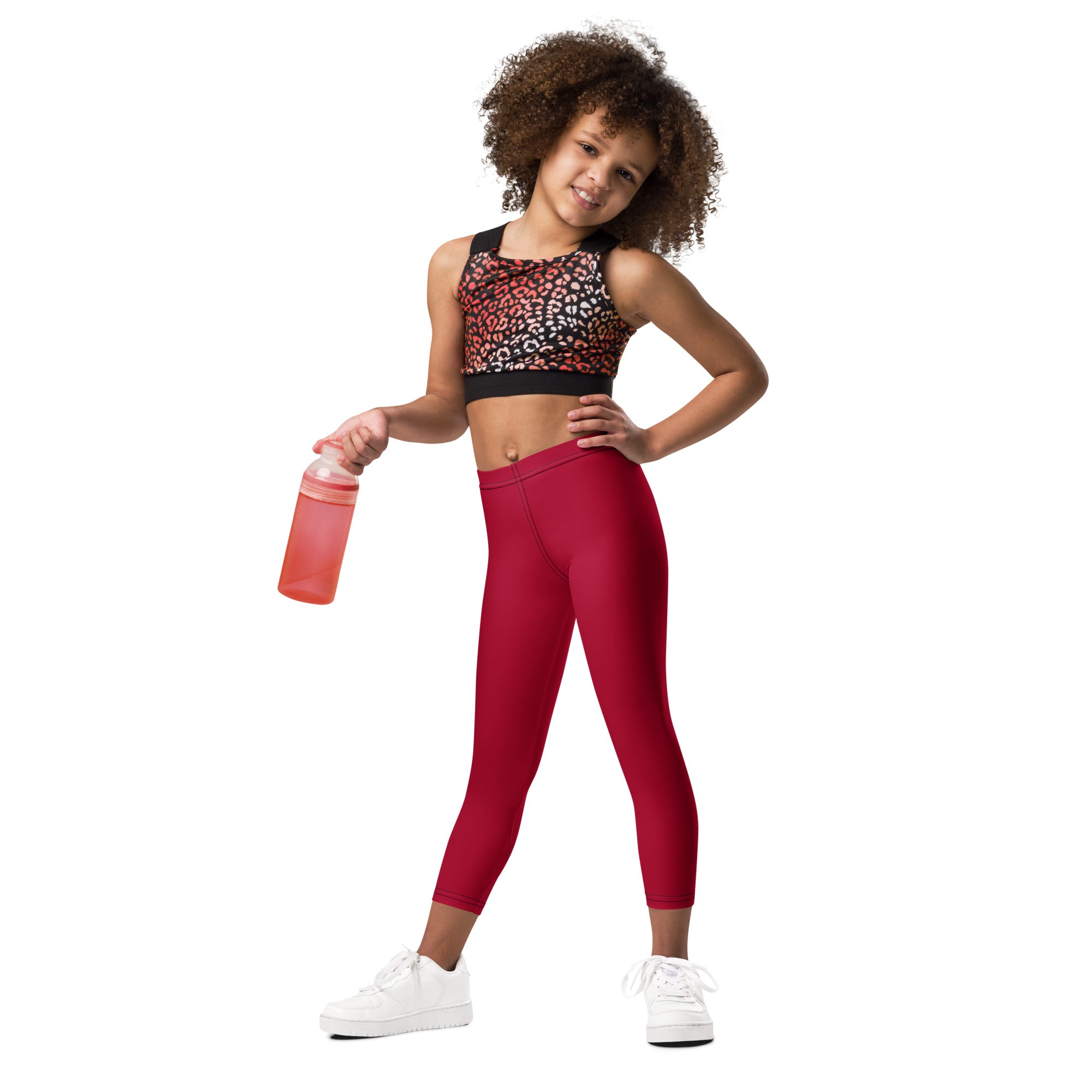 A young girl wearing kids dark red buttery soft leggings and a leopard print sports bra with black trim