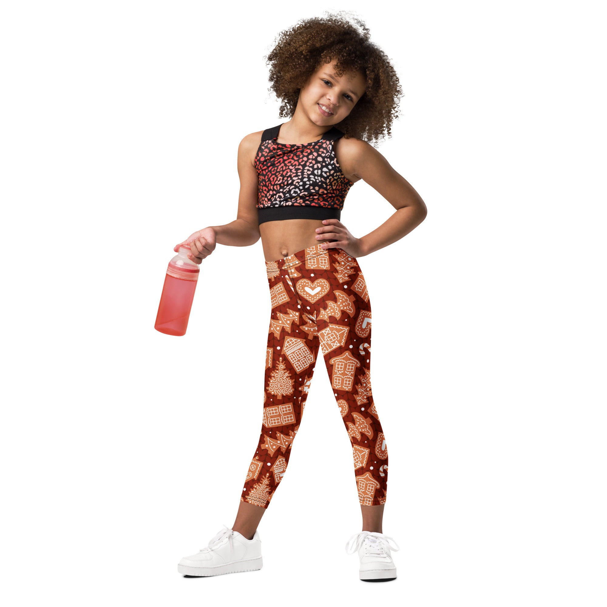 A child wearing kids red gingerbread cookie Christmas buttery soft leggings with festive red and white patterns