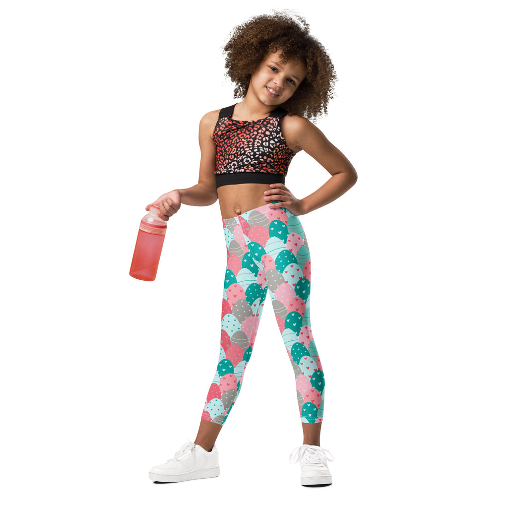 A child wearing girls pink and teal Easter eggs buttery soft leggings with a black and pink leopard-print sports bra