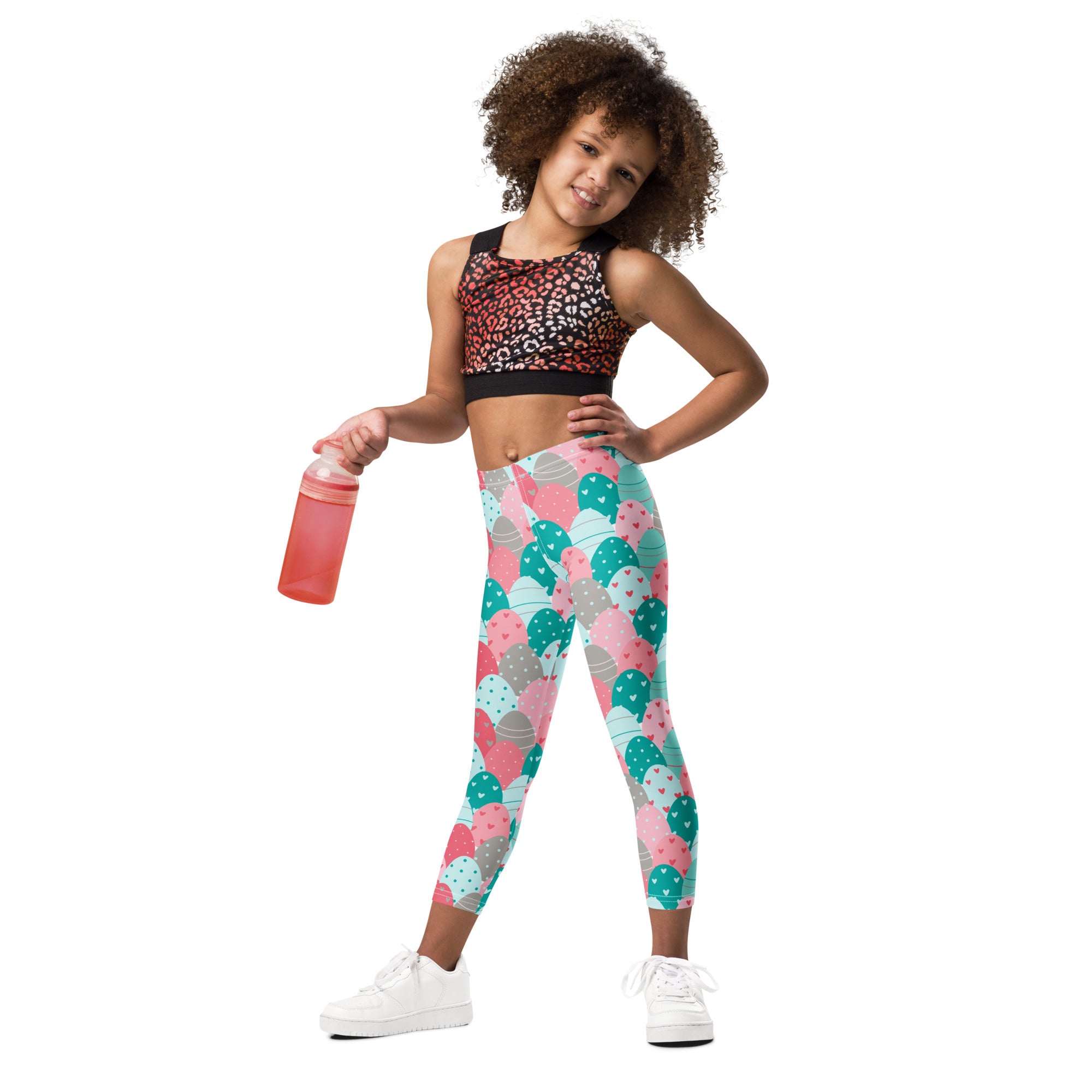 A child wearing girls pink and teal Easter eggs buttery soft leggings with a black and pink leopard-print sports bra