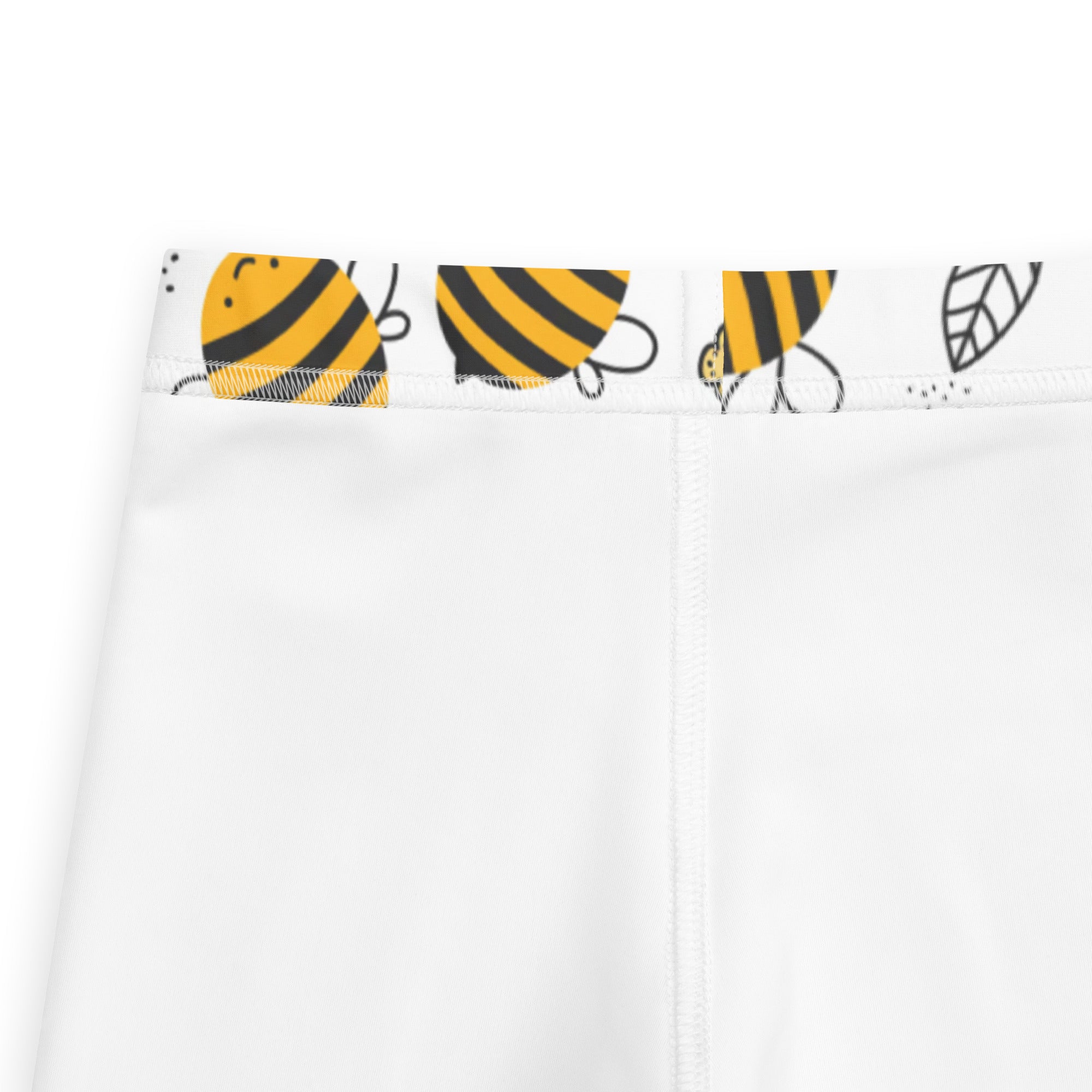 White kids leggings with cute cartoon bee and leaf print on waistband, close-up view