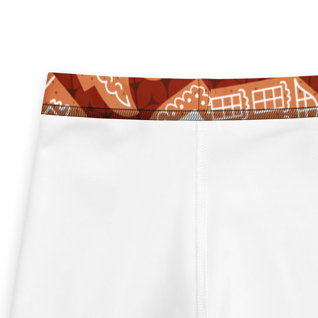 White kids athletic shorts with buttery soft fabric and orange brown waistband featuring gingerbread house line art