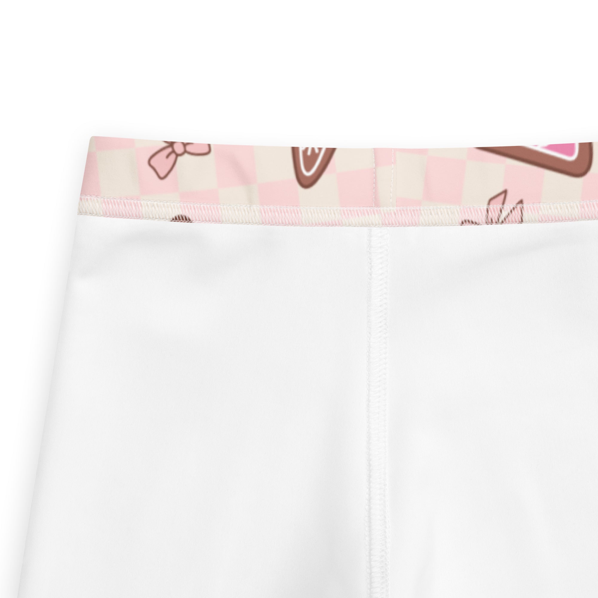 White girls leggings with a pink and beige checkered waistband featuring cartoon bows and chocolate-themed designs