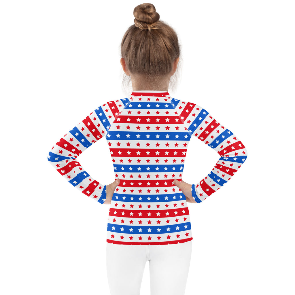 A girl wearing a kids red white and blue stars and stripes USA long sleeve rash guard swim shirt with UPF 50+