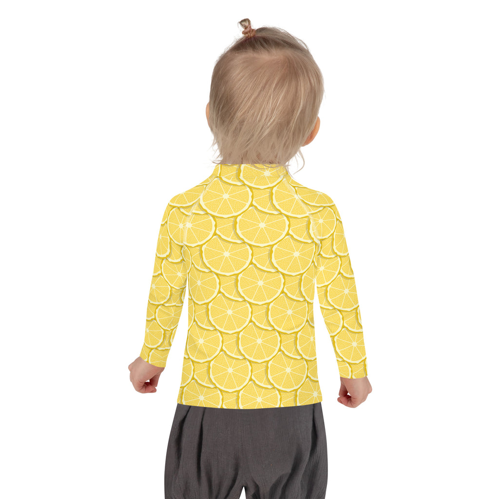 A child wearing a kids lemon long sleeve rash guard swim shirt with upf 50 plus featuring sliced lemon pattern