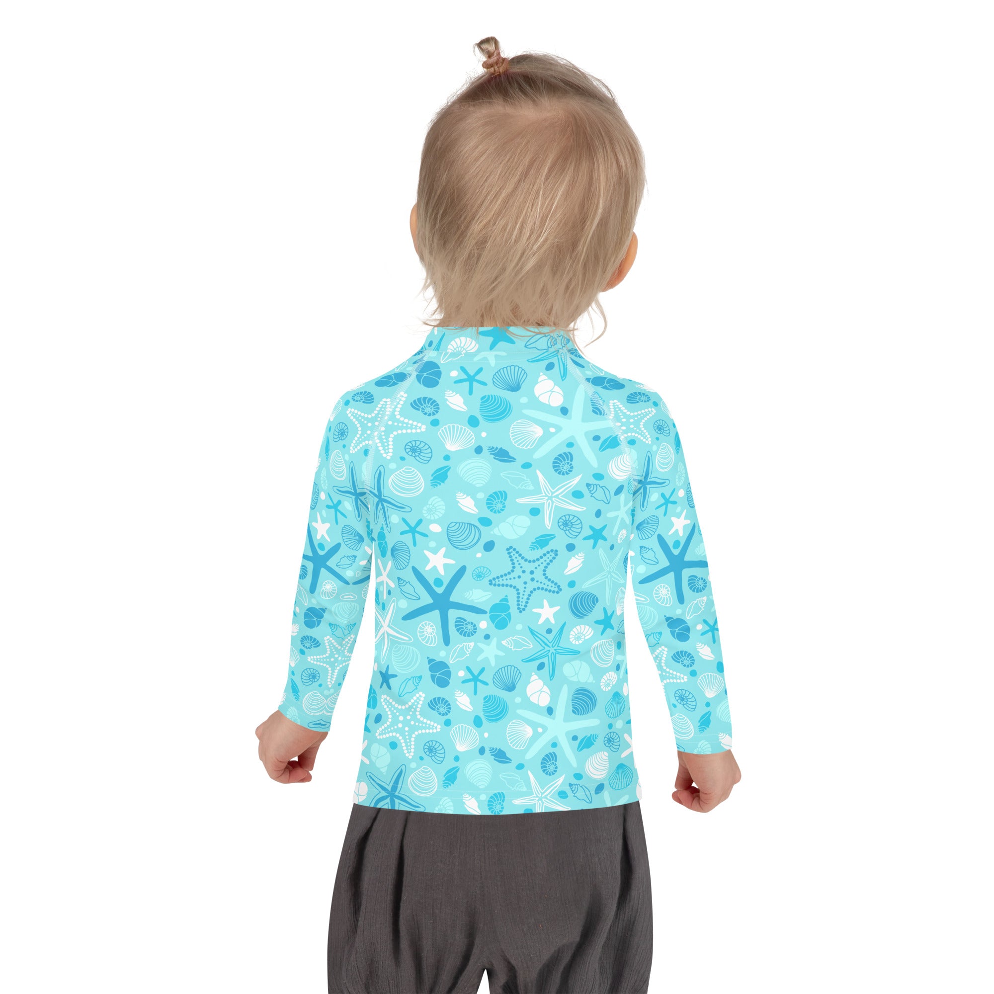 A child wearing a light blue kids starfish and seashell long sleeve rash guard swim shirt with UPF 50+ protection