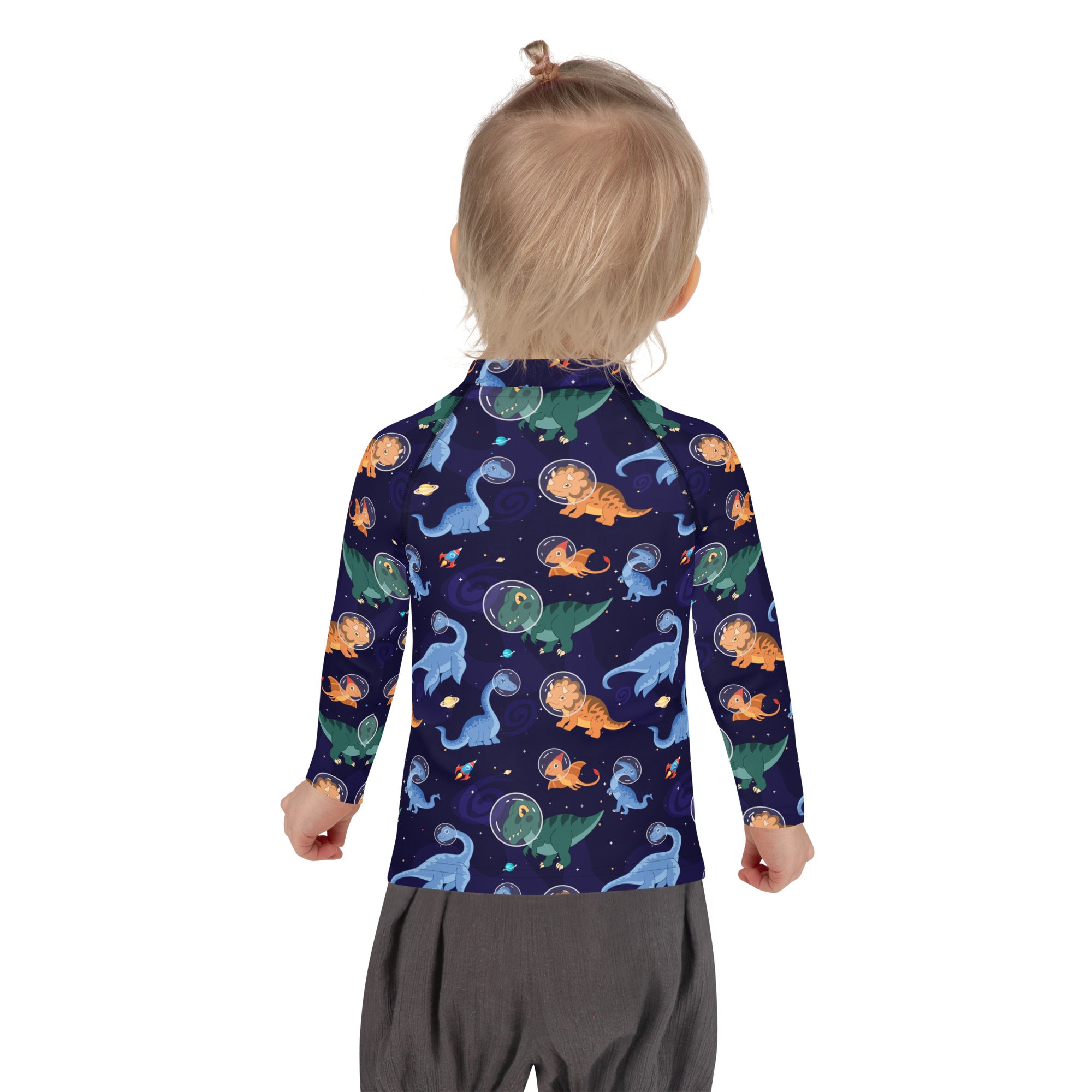 A child wearing a navy blue kids dinosaurs in space long sleeve rash guard swim shirt with colorful dinosaur pattern and upf 50+