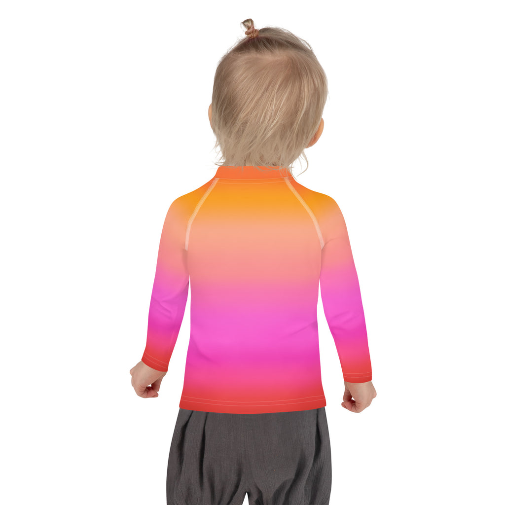 A child wearing a girls sunset ombre long sleeve rash guard swim shirt with vibrant orange to pink hues and UPF 50+ protection