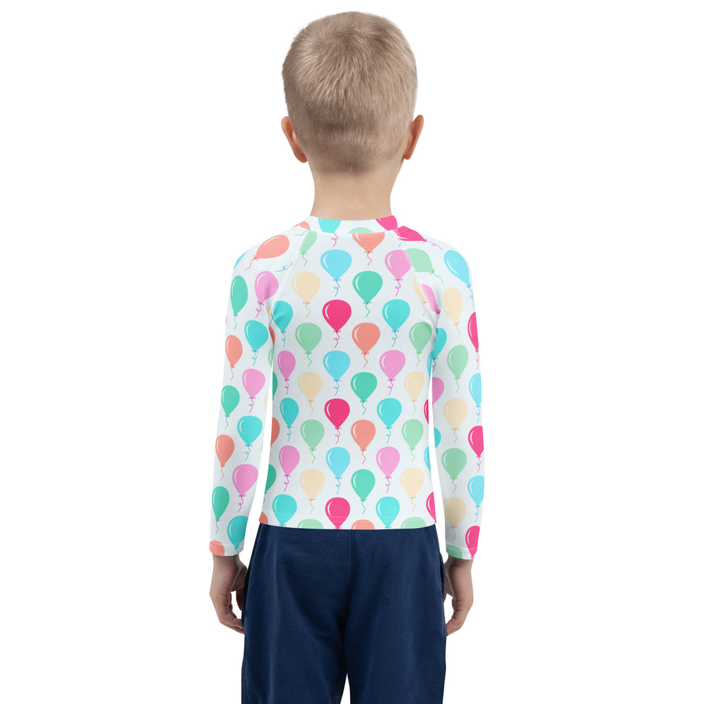 A child wearing a birthday boy colorful balloons long sleeve rash guard swim shirt with upf 50 plus and multicolored balloon pattern