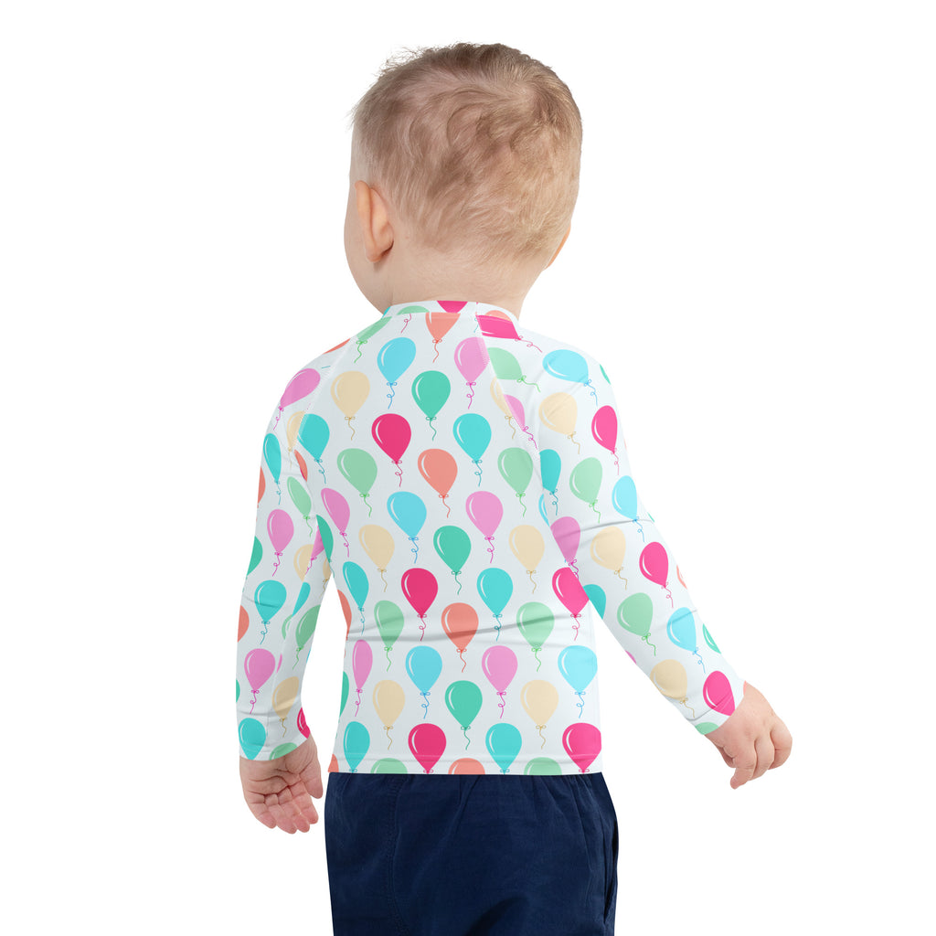 A child wearing a birthday boy colorful balloons long sleeve rash guard swim shirt with upf 50 plus in white