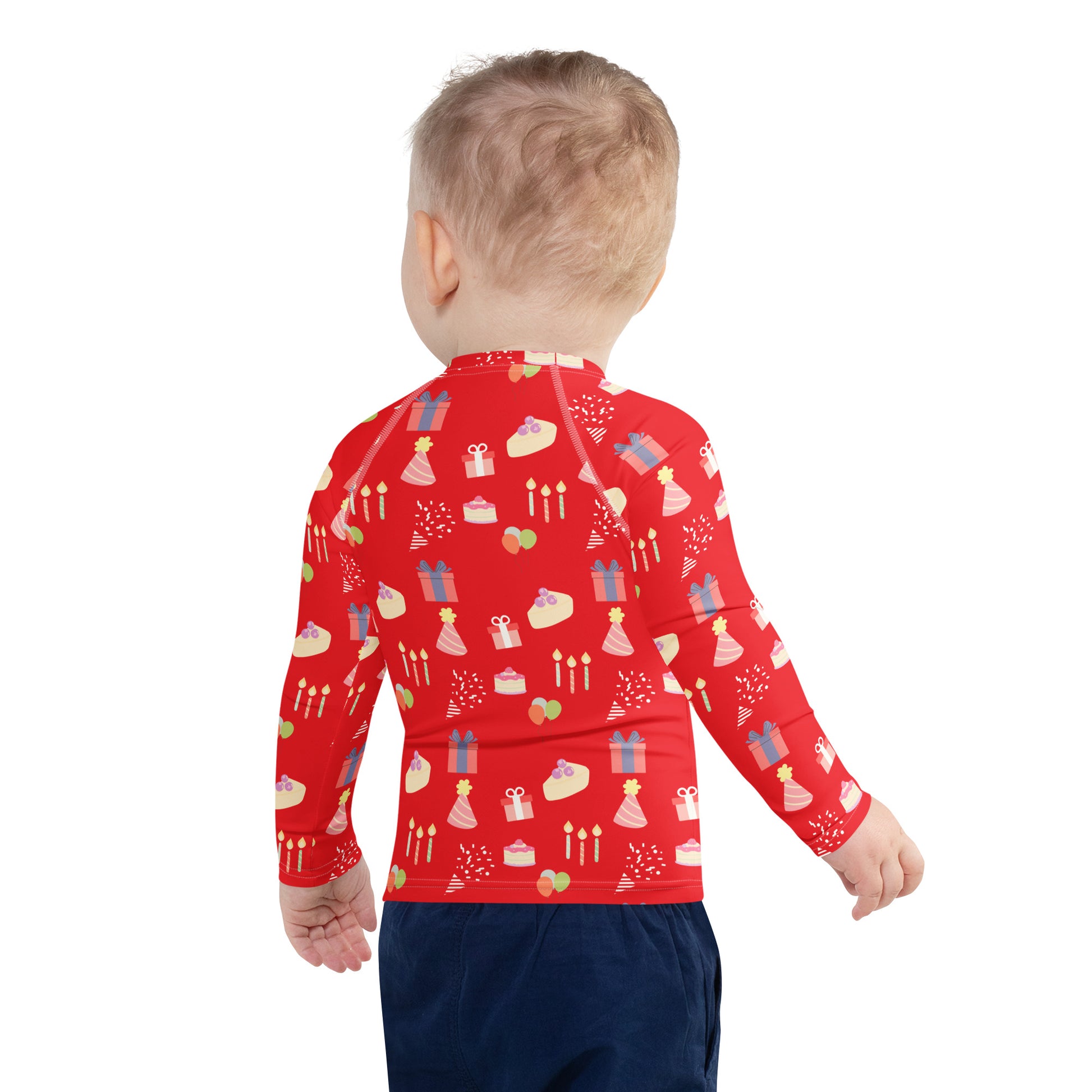 Toddler wearing a red long-sleeve shirt with birthday pattern on a white background