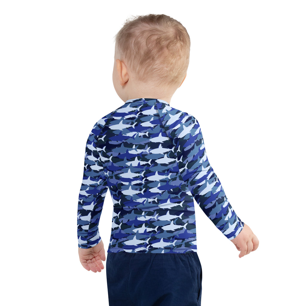A child wearing a kids blue shark long sleeve rash guard swim shirt with upf 50 plus and shark camouflage pattern